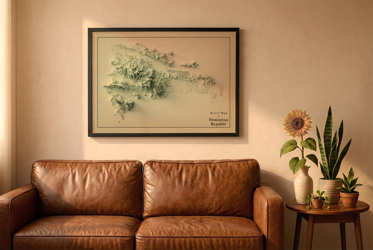 Dominican Republic vintage relief map in a black frame above a brown leather sofa. Boho living room with warm sunlight, sunflower, and indoor plants on a wooden side table