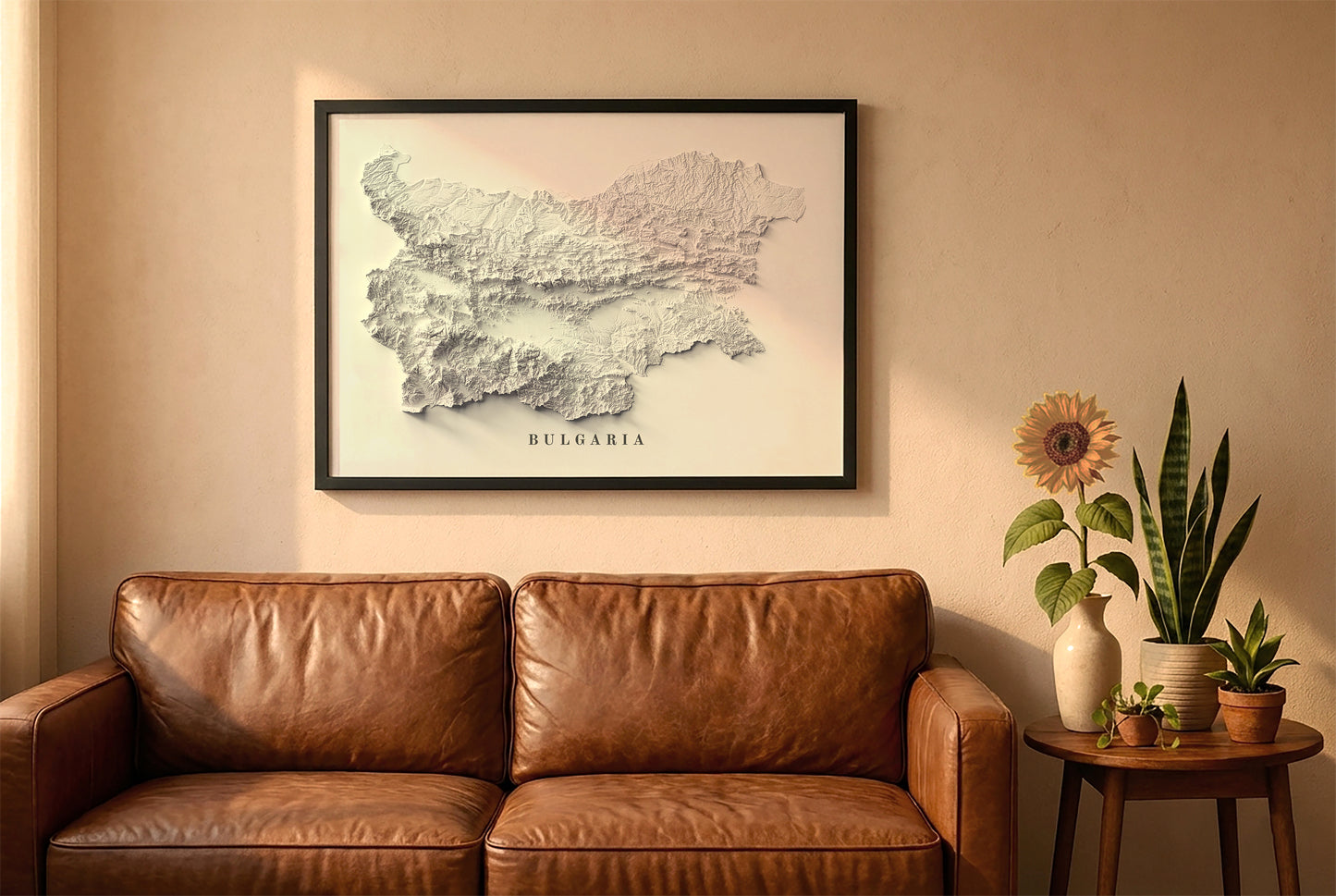 Bulgaria relief map in a black frame above a brown leather sofa. Boho living room with warm sunlight, sunflower, and indoor plants on a wooden side table