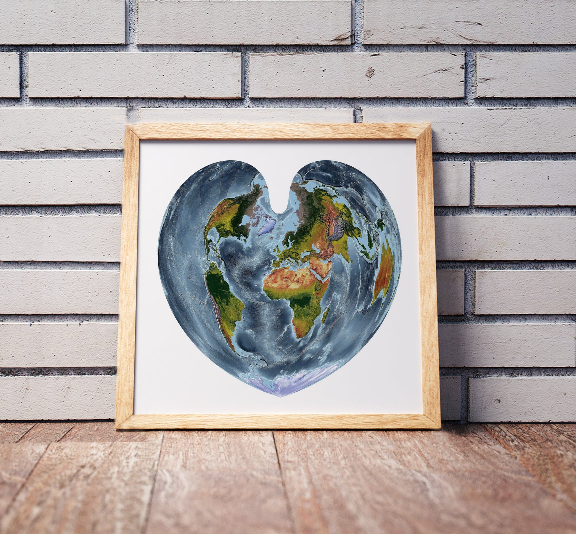 Boone projection shaded relief world map in a wooden frame. Realistic terrain art print for home decor, displayed against a brick wall