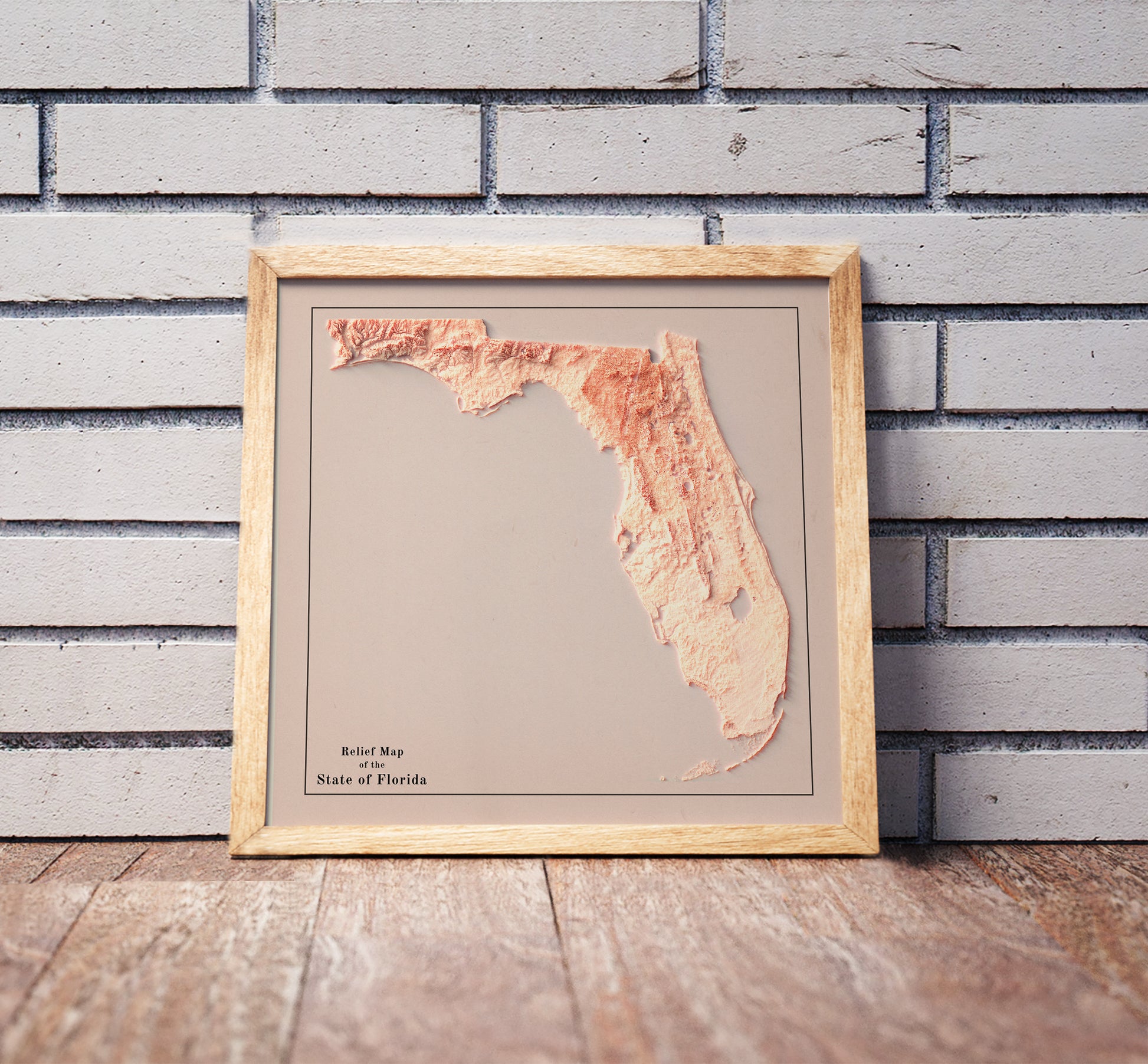 Vintage Florida shaded relief map in a wooden frame. Realistic terrain art print for home decor, displayed against a brick wall