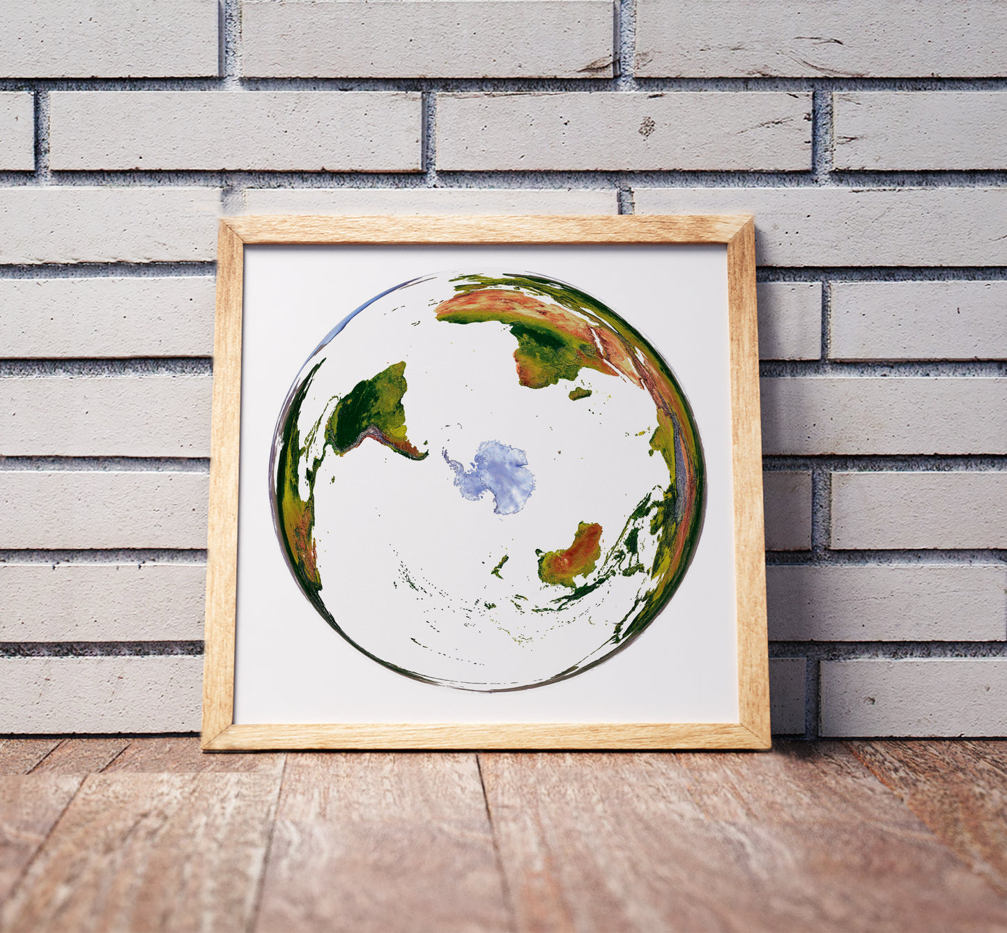 WGS 1984 Grid South projection shaded relief world map in a wooden frame. Realistic terrain art print for home decor, displayed against a brick wall