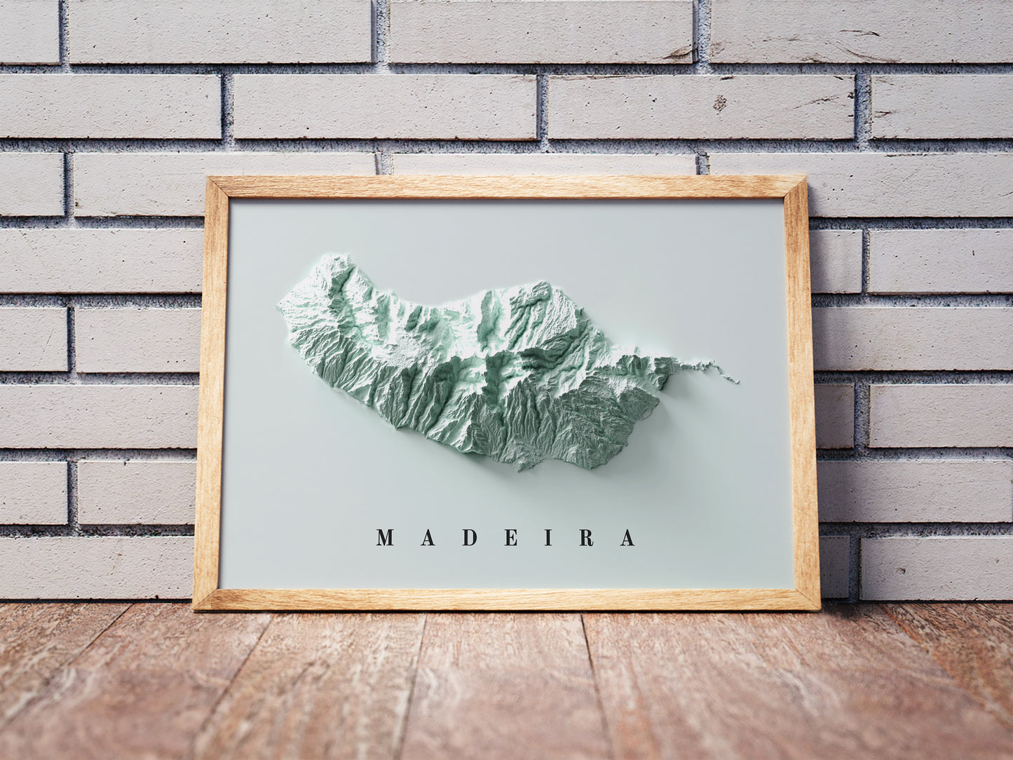 Madeira Island, Portugal, shaded relief map in a wooden frame. Realistic terrain art print for home decor, displayed against a brick wall