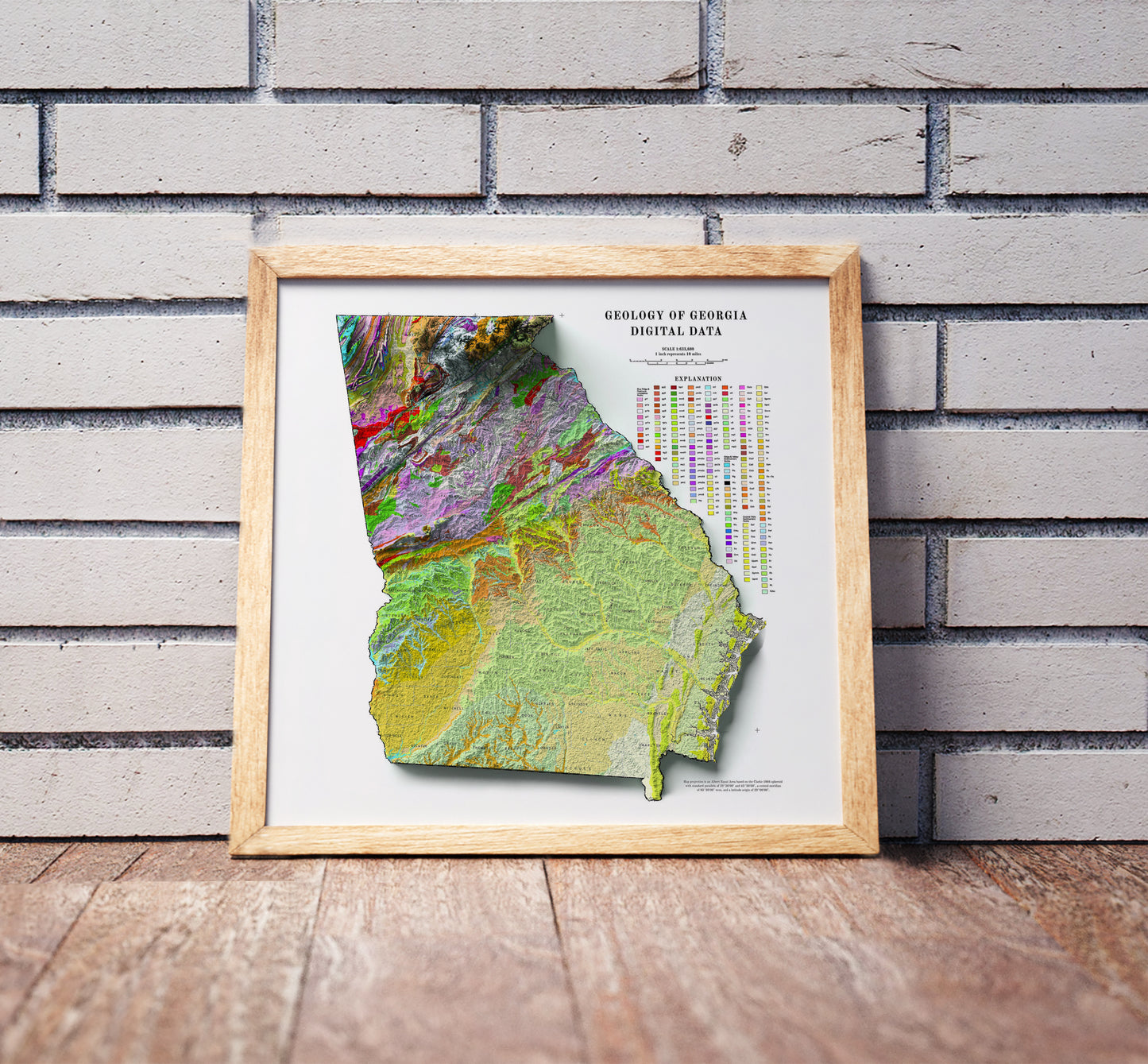 Vintage Georgia shaded relief map in a wooden frame. Realistic terrain art print for home decor, displayed against a brick wall