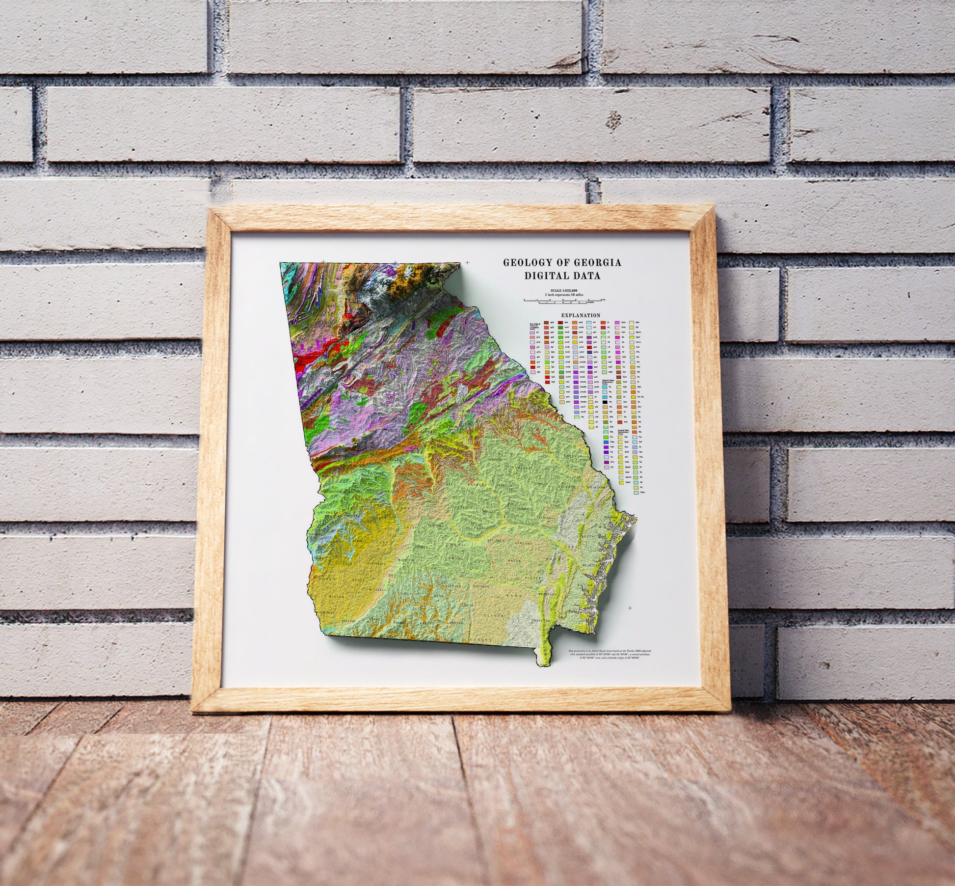 Vintage Georgia shaded relief map in a wooden frame. Realistic terrain art print for home decor, displayed against a brick wall