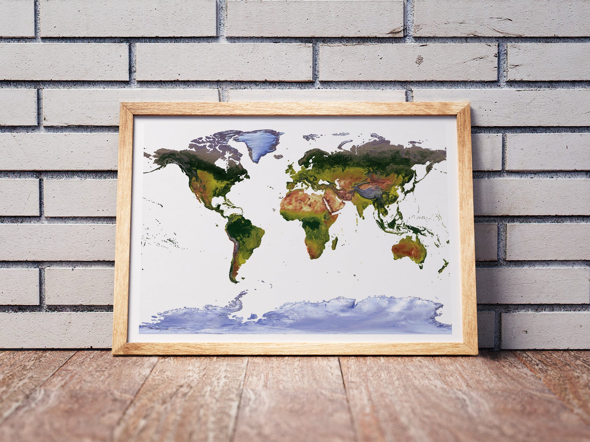 Gall Stereographic projection shaded relief world map in a wooden frame. Realistic terrain art print for home decor, displayed against a brick wall
