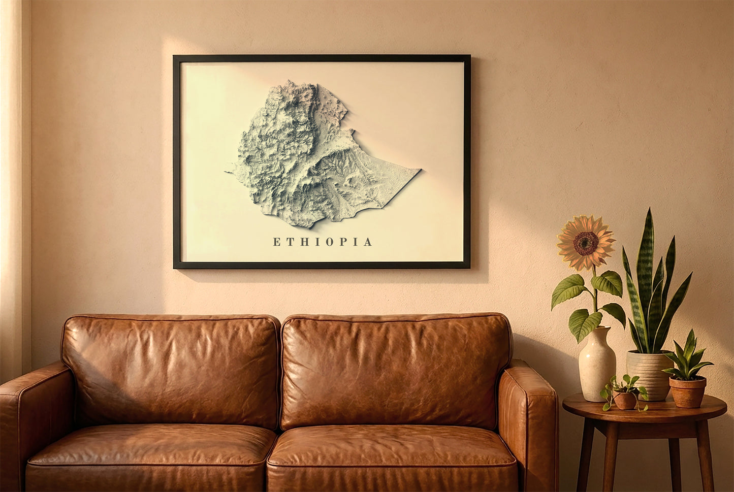 Ethiopia relief map in a black frame above a brown leather sofa. Boho living room with warm sunlight, sunflower, and indoor plants on a wooden side table