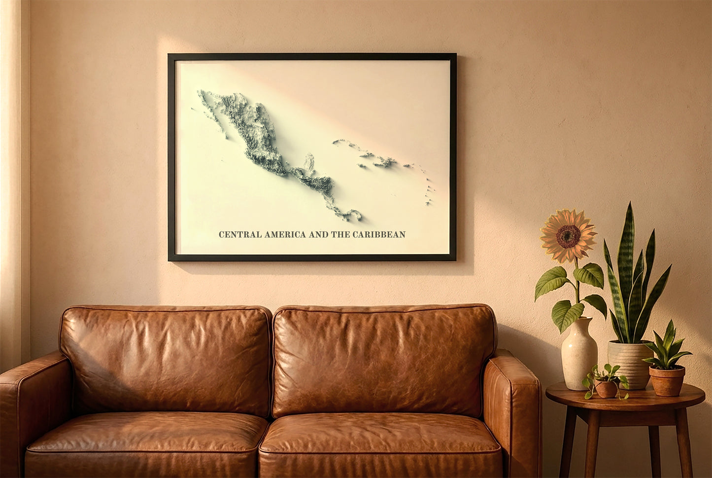 Central America and the Caribbean relief map in a black frame above a brown leather sofa. Boho living room with warm sunlight, sunflower, and indoor plants on a wooden side table