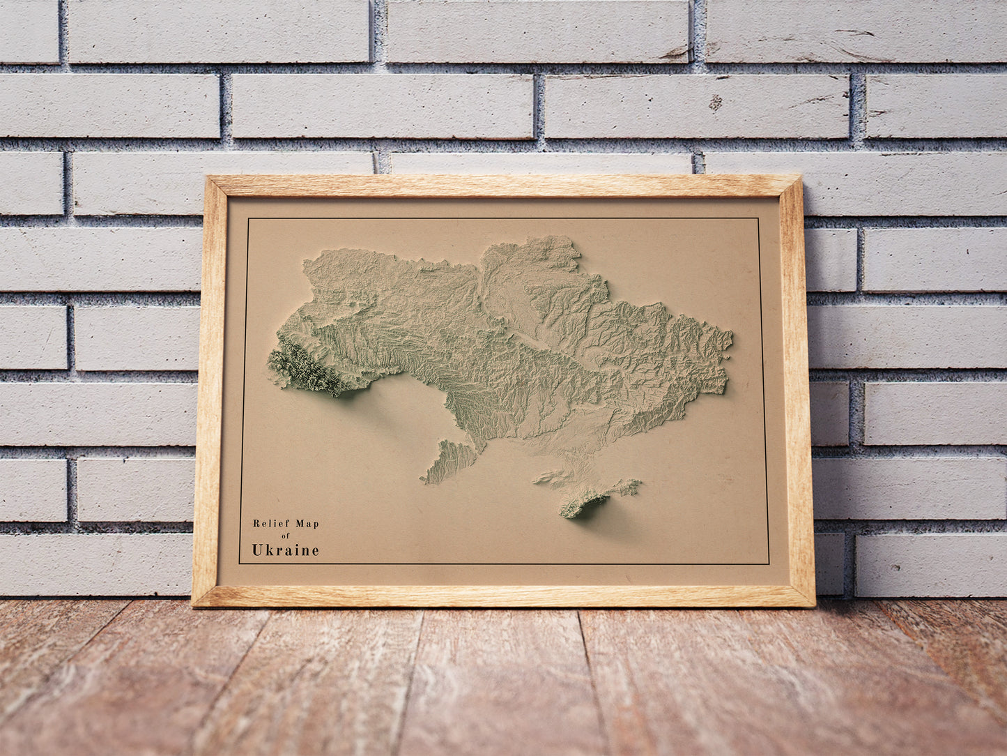 Vintage Ukraine shaded relief map in a wooden frame. Realistic terrain art print for home decor, displayed against a brick wall