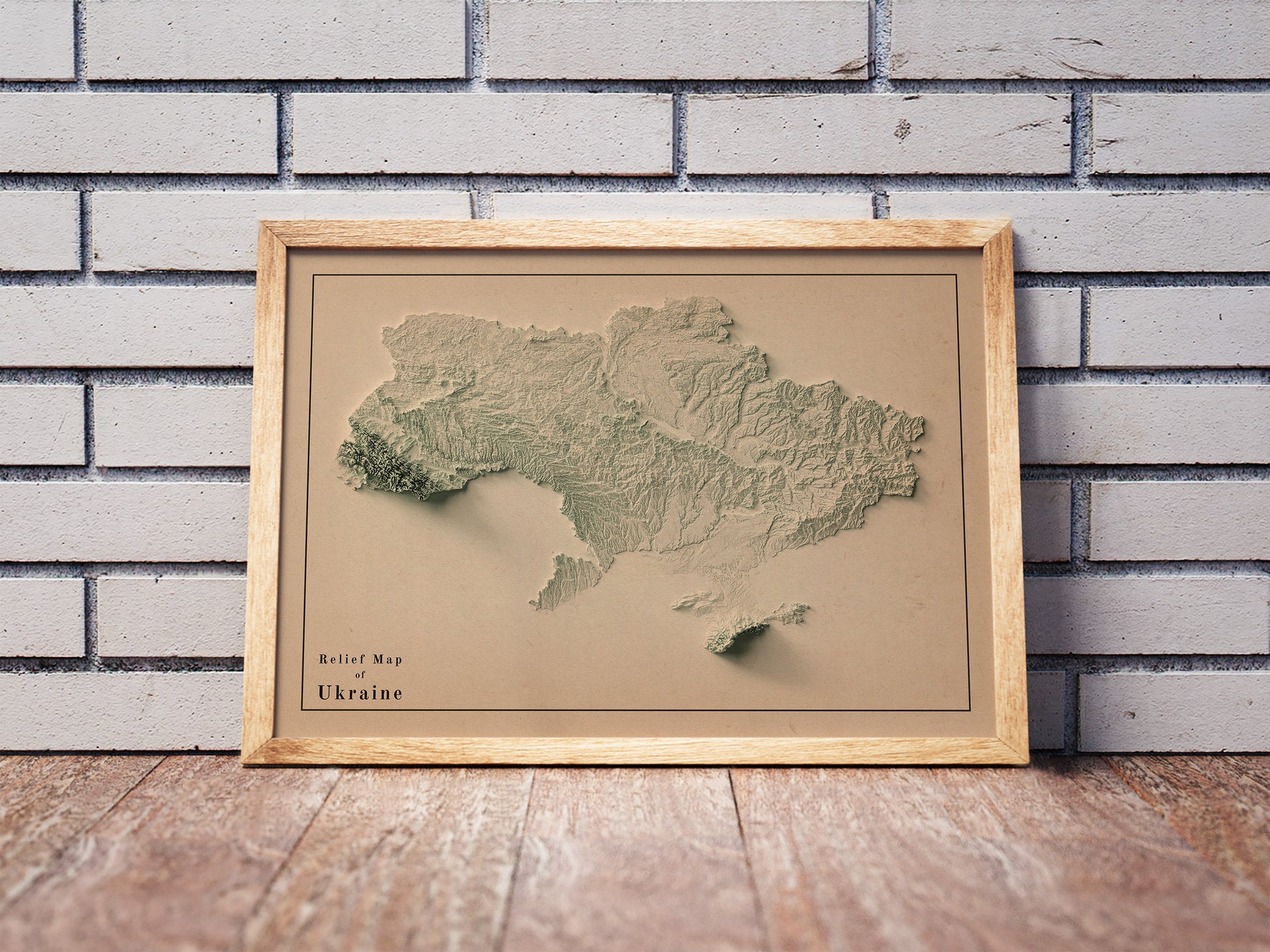 Vintage Ukraine shaded relief map in a wooden frame. Realistic terrain art print for home decor, displayed against a brick wall