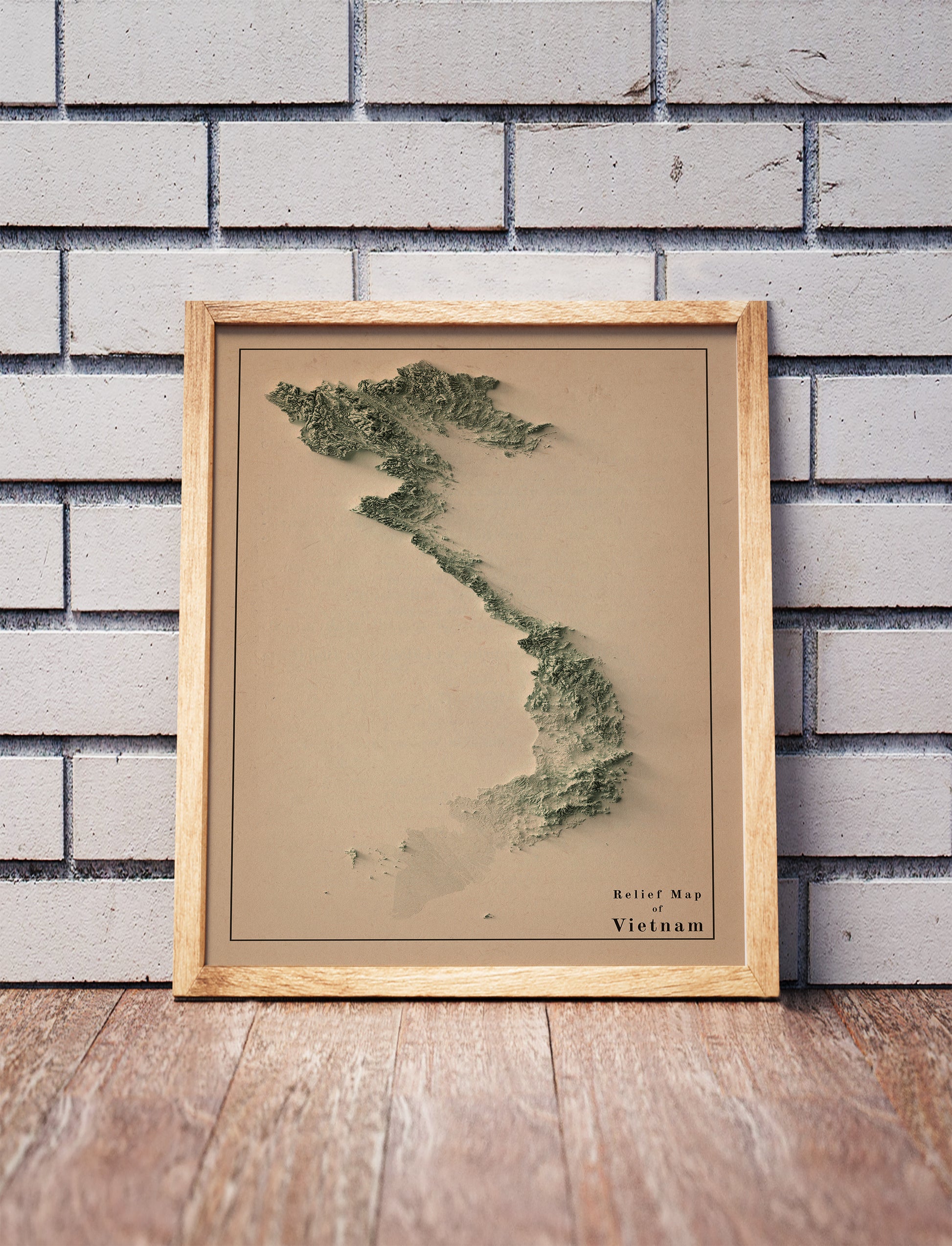 Vintage Vietnam shaded relief map in a wooden frame. Realistic terrain art print for home decor, displayed against a brick wall