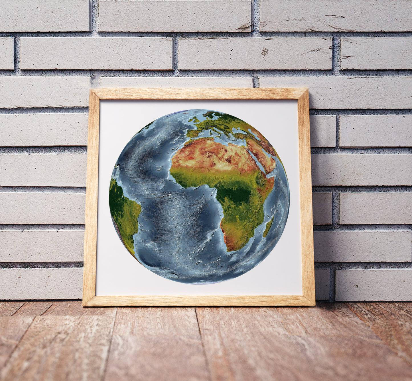 Vertical Perspective projection shaded relief world map in a wooden frame. Realistic terrain art print for home decor, displayed against a brick wall