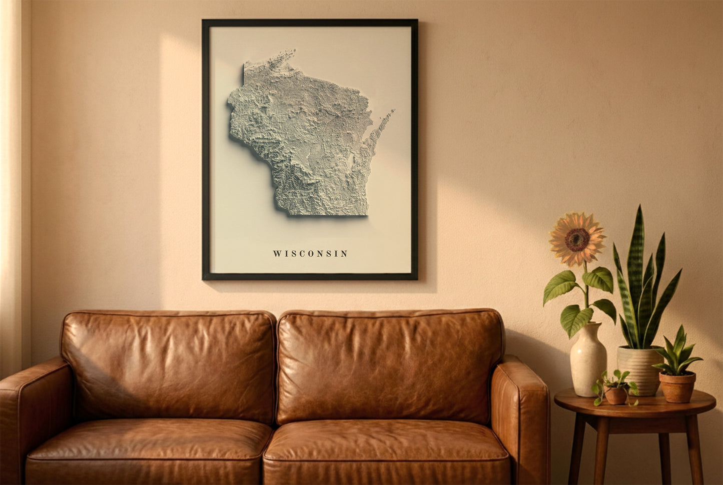 Wisconsin relief map in a black frame above a brown leather sofa. Boho living room with warm sunlight, sunflower, and indoor plants on a wooden side table