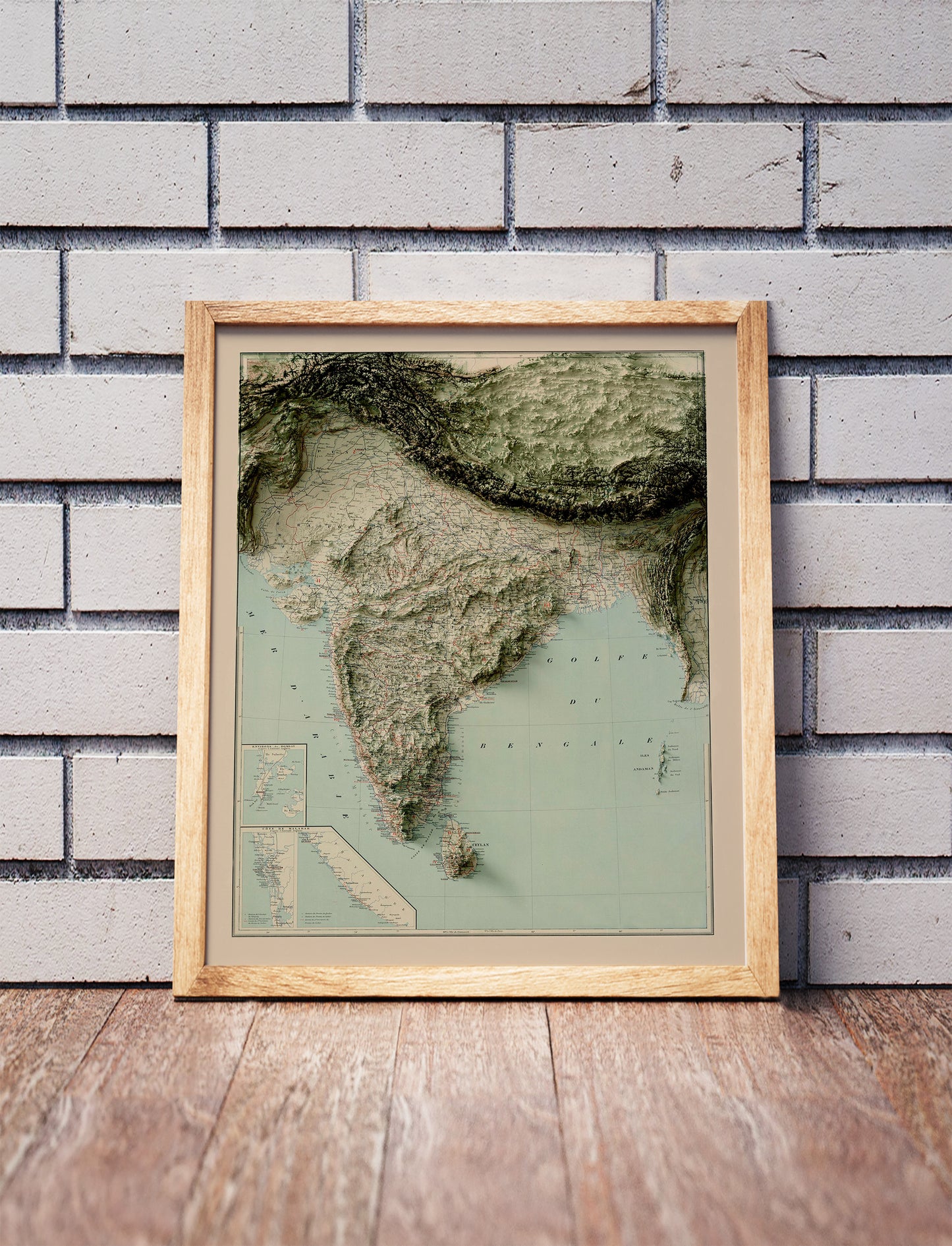 Vintage India shaded relief map in a wooden frame. Realistic terrain art print for home decor, displayed against a brick wall