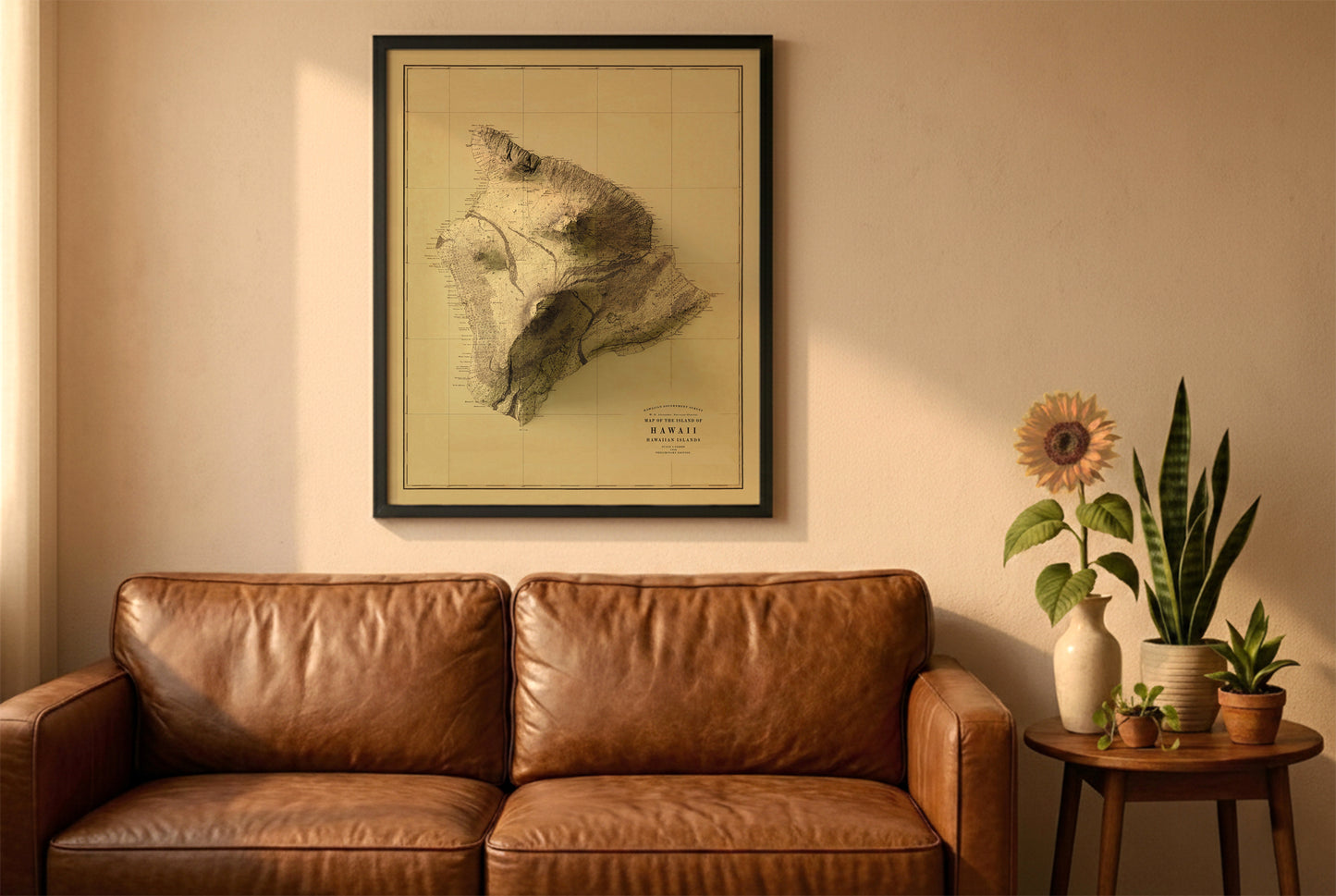Hawaii Island vintage relief map in a black frame above a brown leather sofa. Boho living room with warm sunlight, sunflower, and indoor plants on a wooden side table