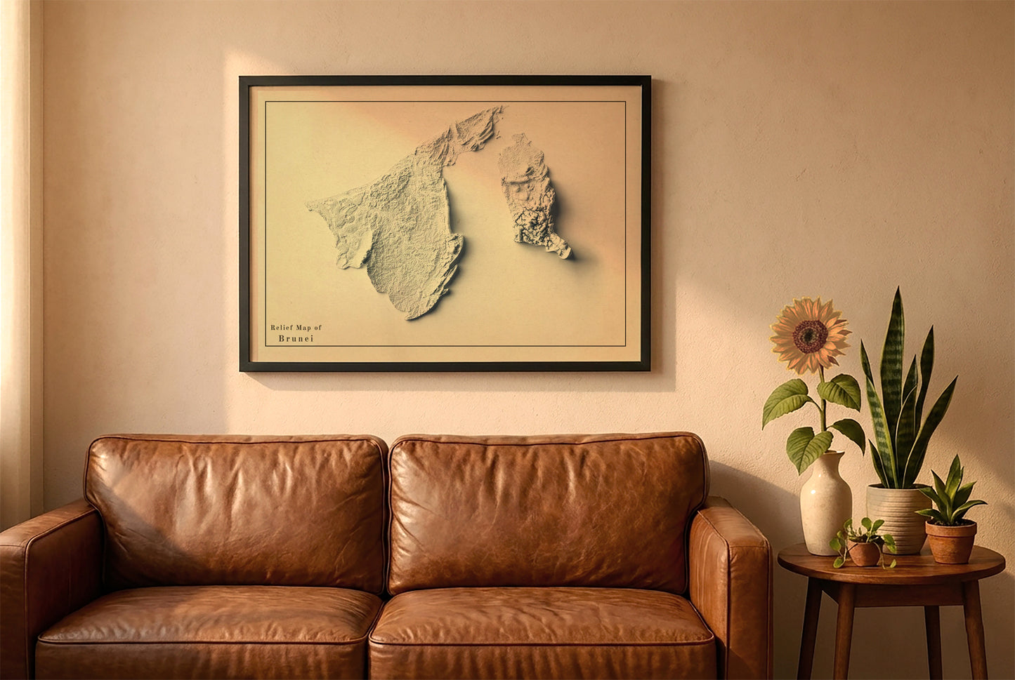 Brunei vintage relief map in a black frame above a brown leather sofa. Boho living room with warm sunlight, sunflower, and indoor plants on a wooden side table