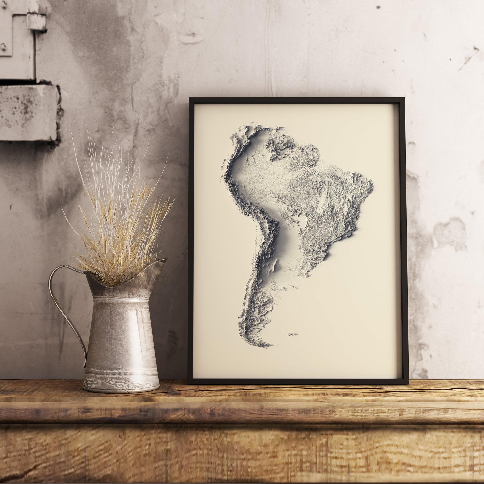 South America shaded relief map in black frame. Realistic terrain art print for home decor, displayed on rustic wooden table