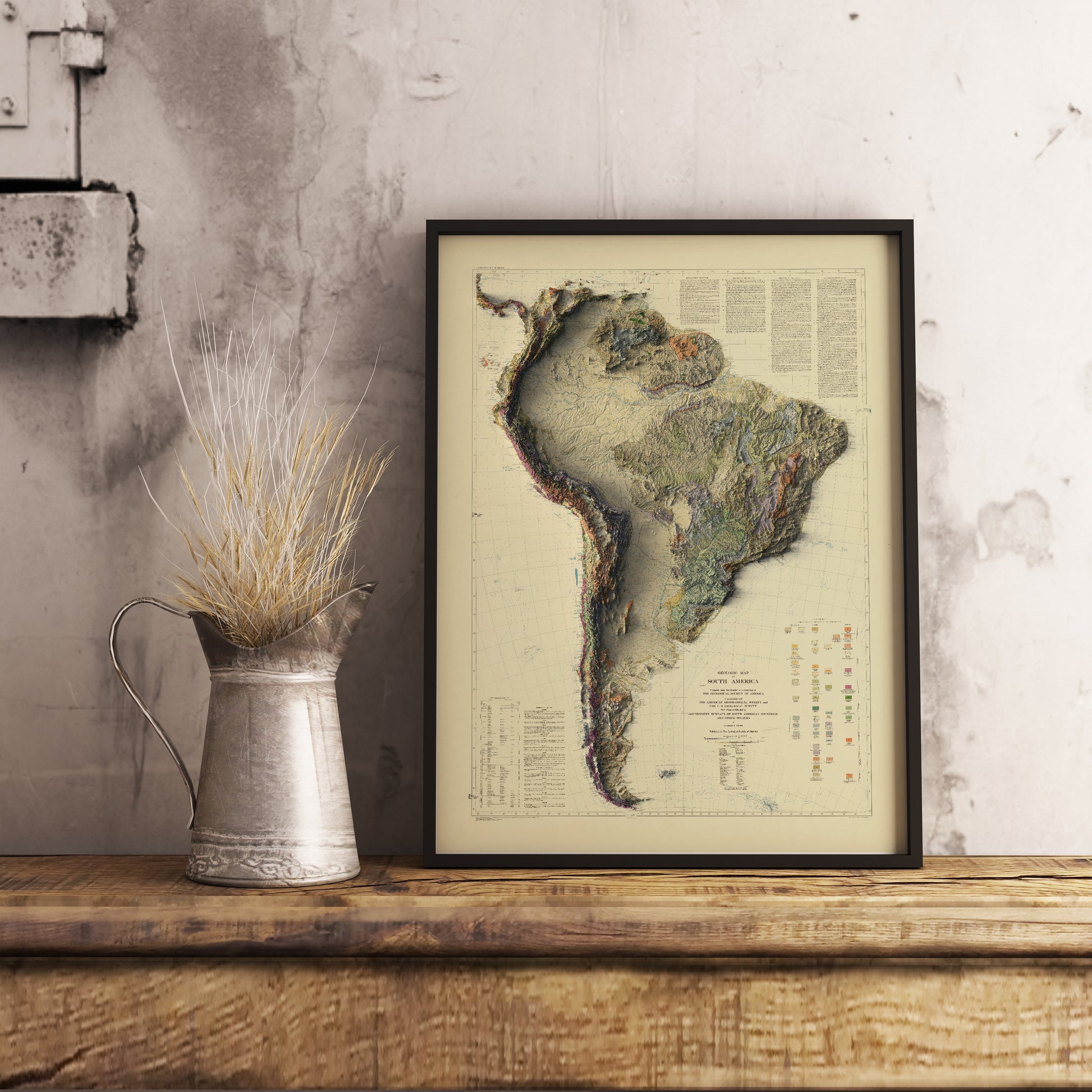Vintage South America shaded relief map in black frame. Realistic terrain art print for home decor, displayed on rustic wooden table
