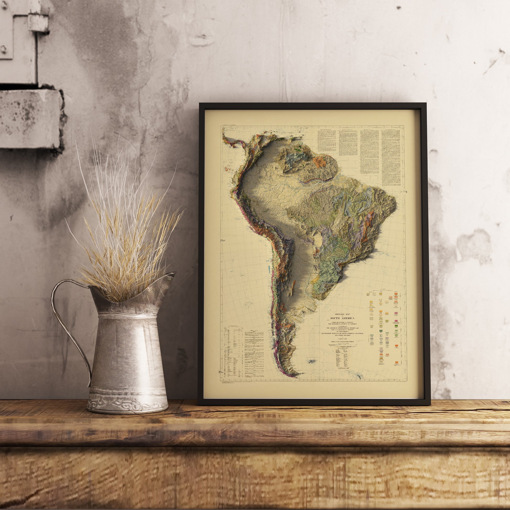 Vintage South America shaded relief map in black frame. Realistic terrain art print for home decor, displayed on rustic wooden table