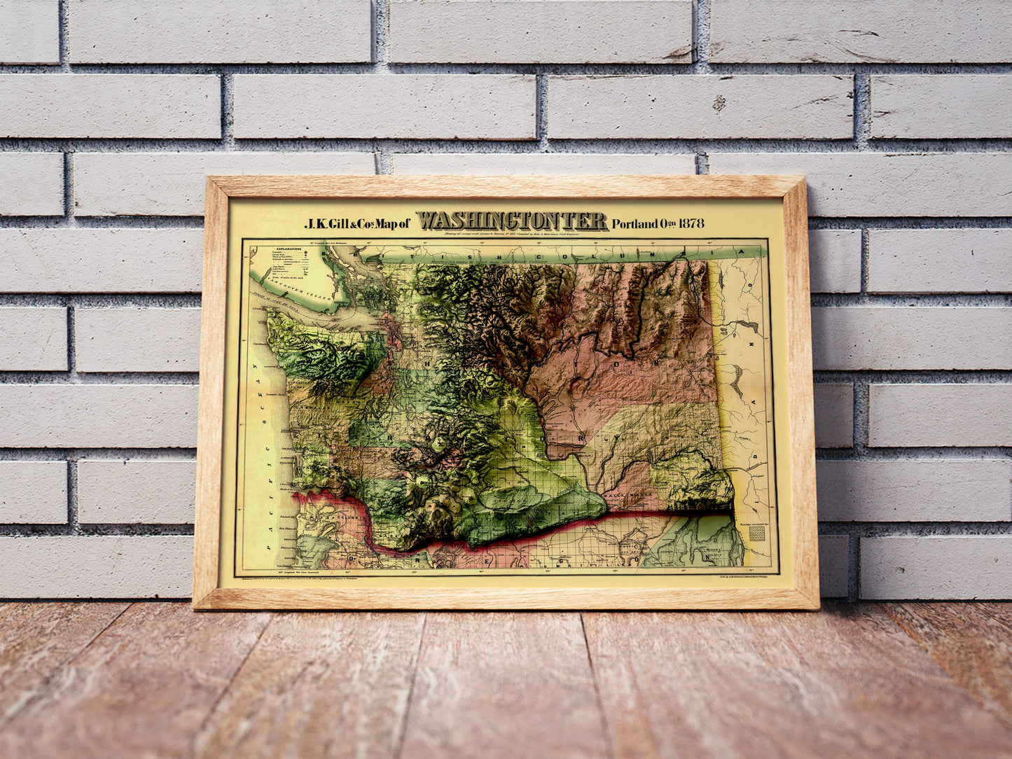 Vintage Washington shaded relief map in a wooden frame. Realistic terrain art print for home decor, displayed against a brick wall