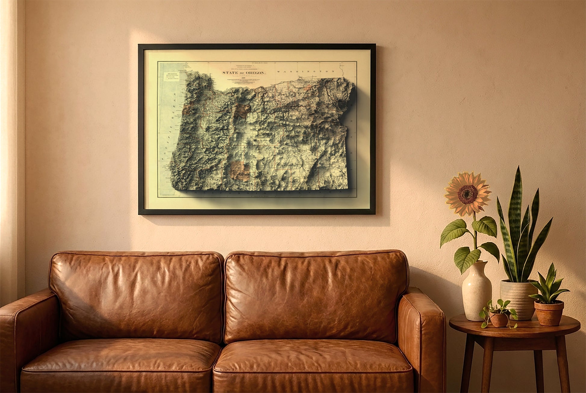 Oregon vintage relief map in a black frame above a brown leather sofa. Boho living room with warm sunlight, sunflower, and indoor plants on a wooden side table