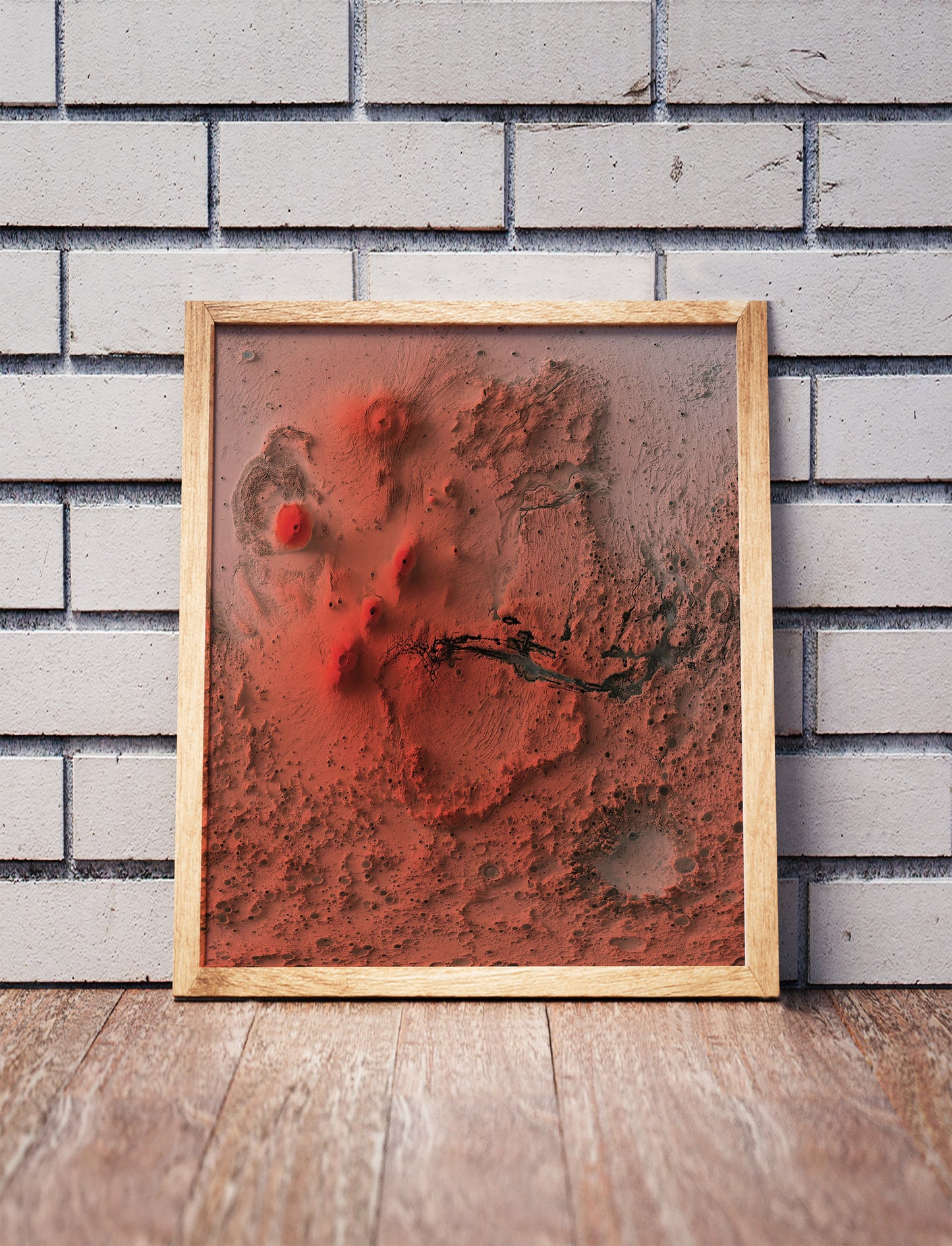 Mars shaded relief map in a wooden frame. Realistic terrain art print for home decor, displayed against a brick wall