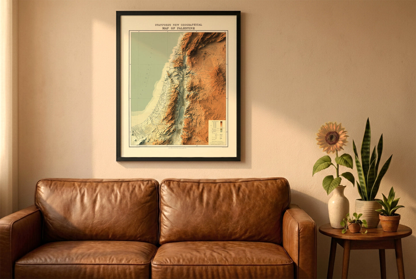 Palestine vintage relief map in a black frame above a brown leather sofa. Boho living room with warm sunlight, sunflower, and indoor plants on a wooden side table