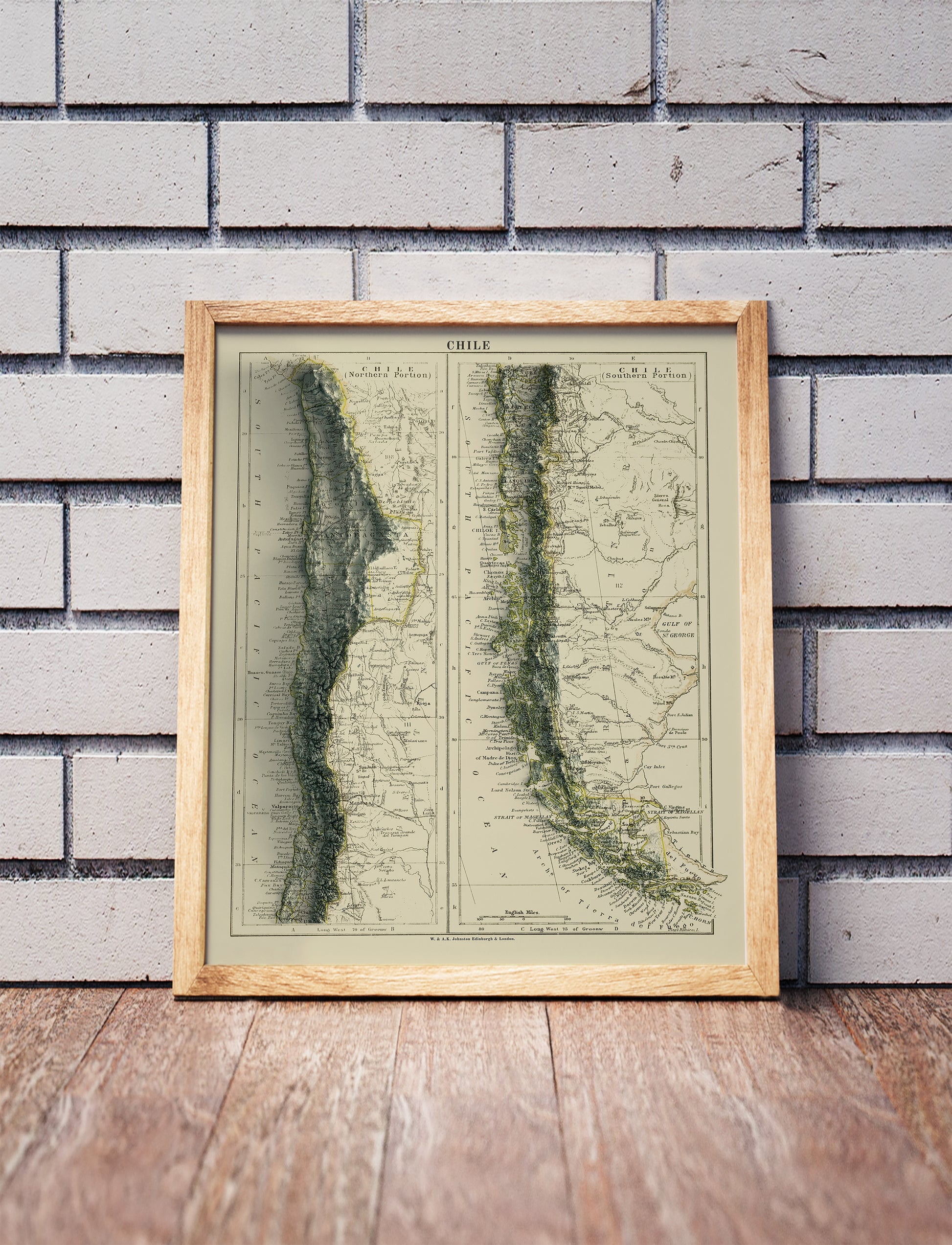 Vintage Chile shaded relief map in a wooden frame. Realistic terrain art print for home decor, displayed against a brick wall