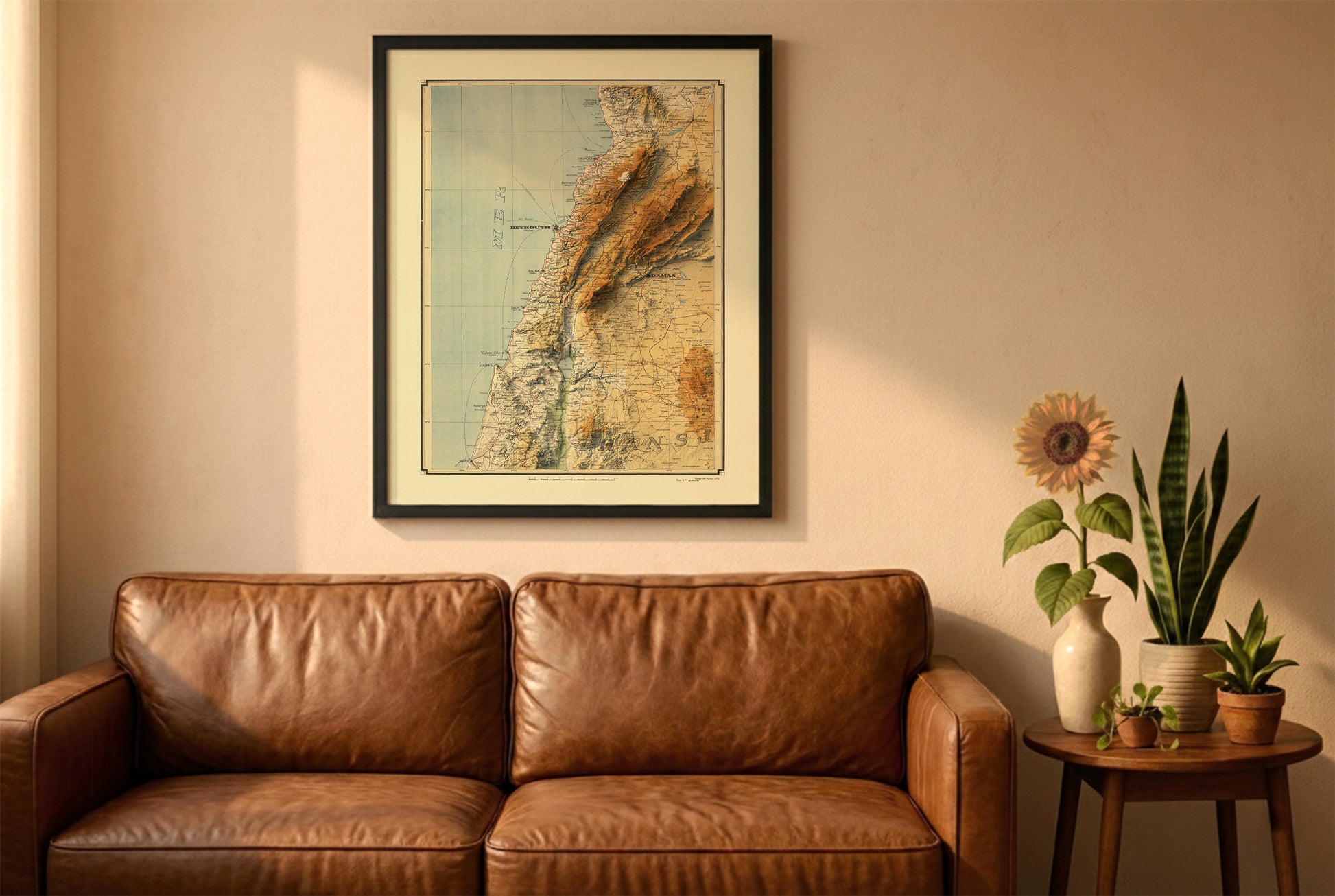 Lebanon vintage relief map in a black frame above a brown leather sofa. Boho living room with warm sunlight, sunflower, and indoor plants on a wooden side table
