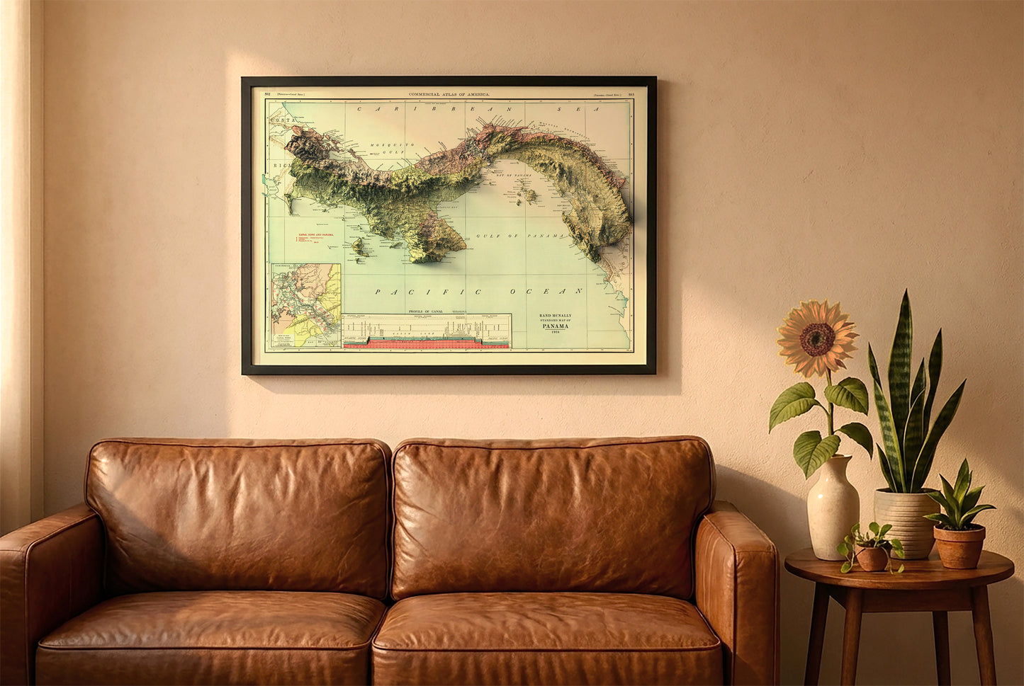 Panama vintage relief map in a black frame above a brown leather sofa. Boho living room with warm sunlight, sunflower, and indoor plants on a wooden side table