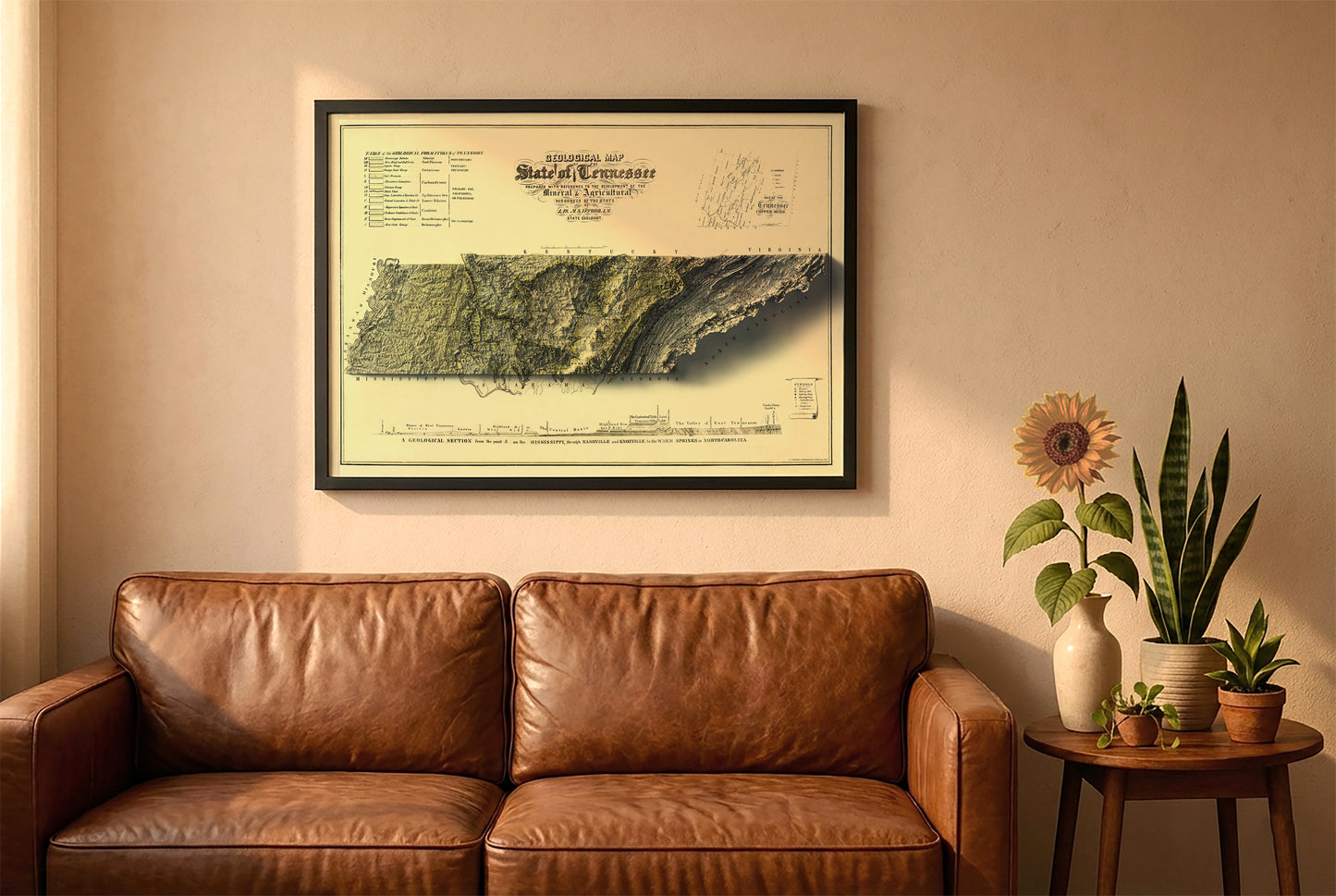 Tennessee vintage relief map in a black frame above a brown leather sofa. Boho living room with warm sunlight, sunflower, and indoor plants on a wooden side table