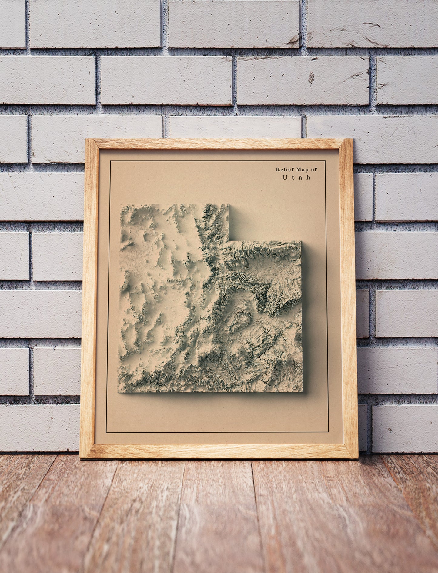 Vintage utah shaded relief map in a wooden frame. Realistic terrain art print for home decor, displayed against a brick wall