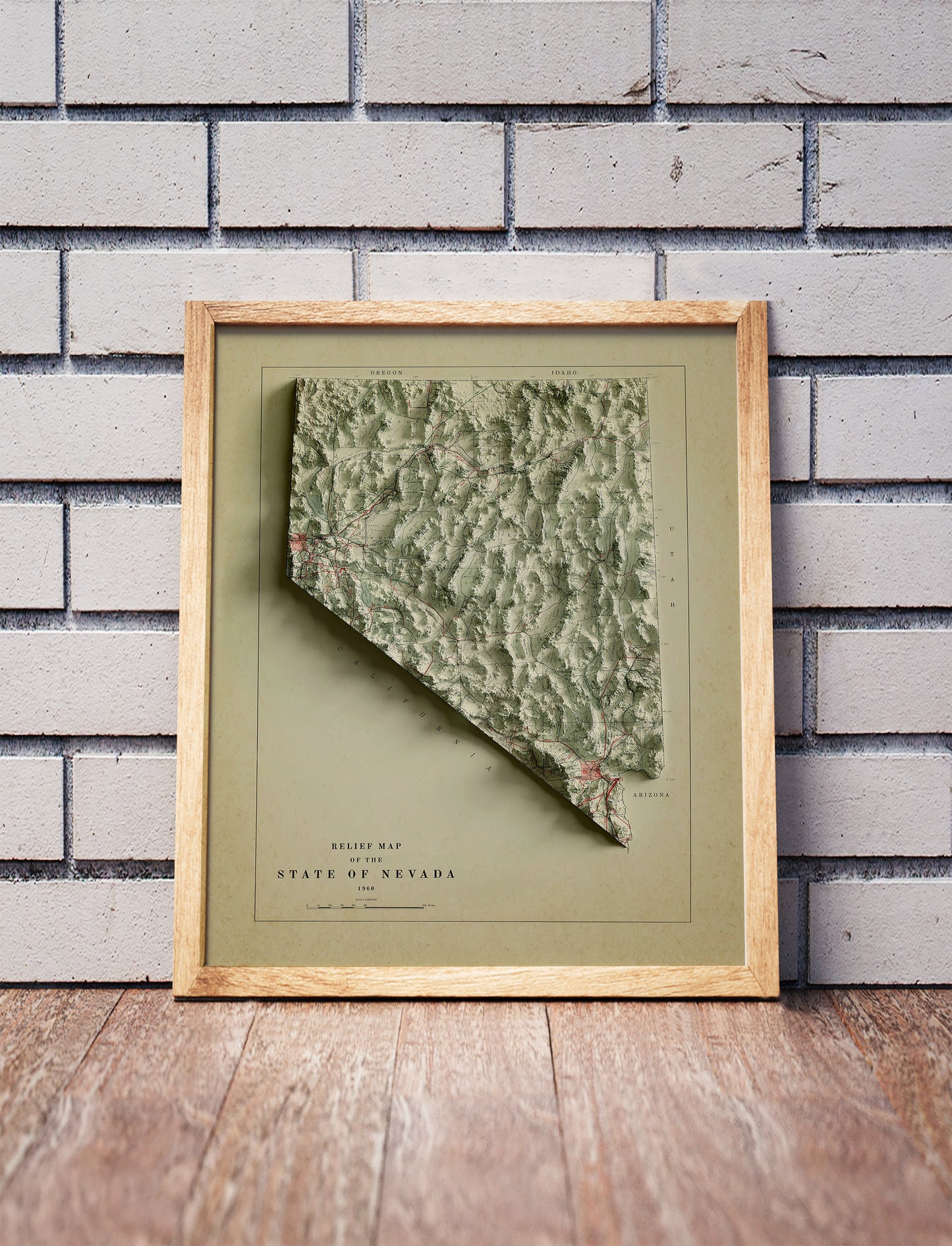 Vintage Nevada shaded relief map in a wooden frame. Realistic terrain art print for home decor, displayed against a brick wall