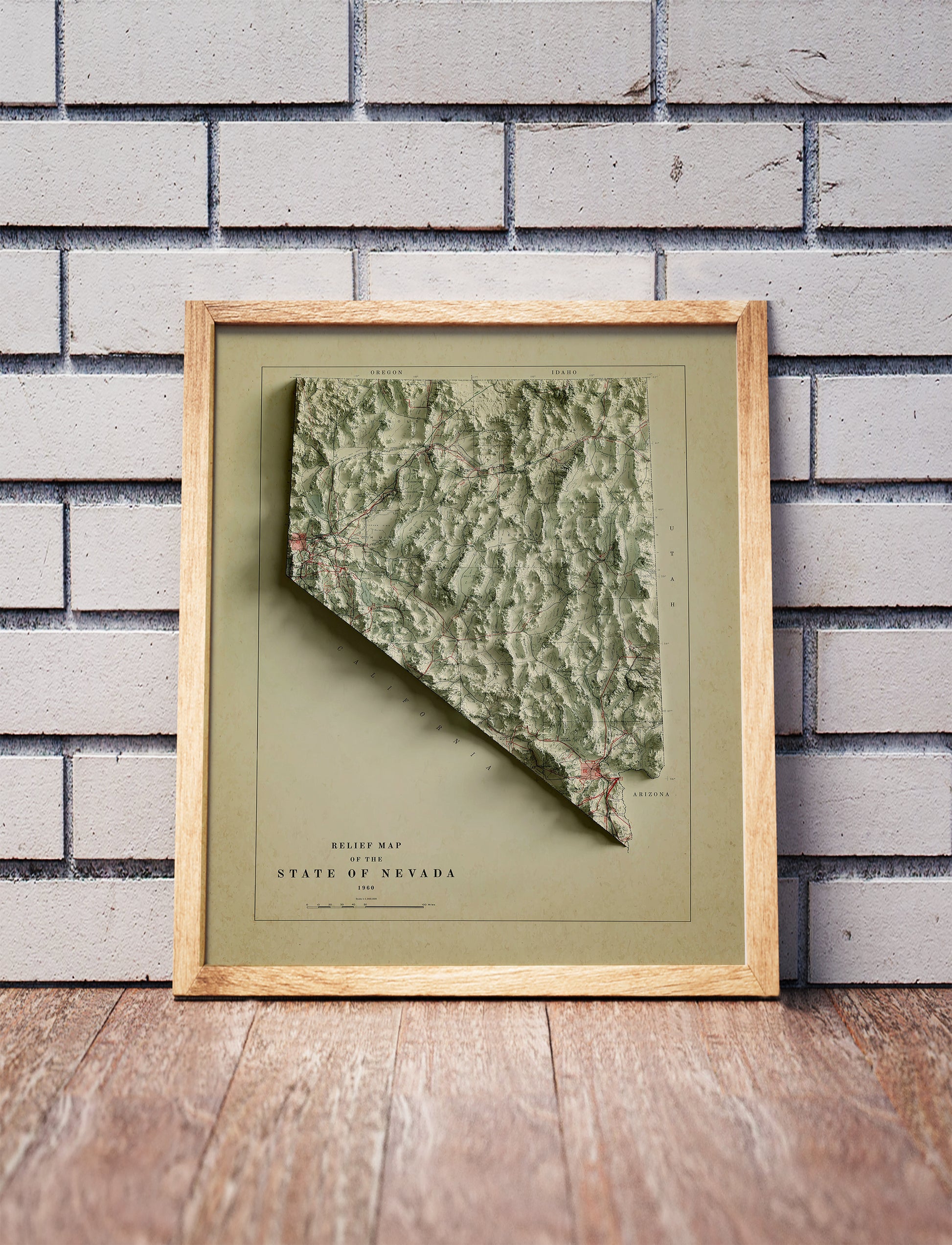 Vintage Nevada shaded relief map in a wooden frame. Realistic terrain art print for home decor, displayed against a brick wall