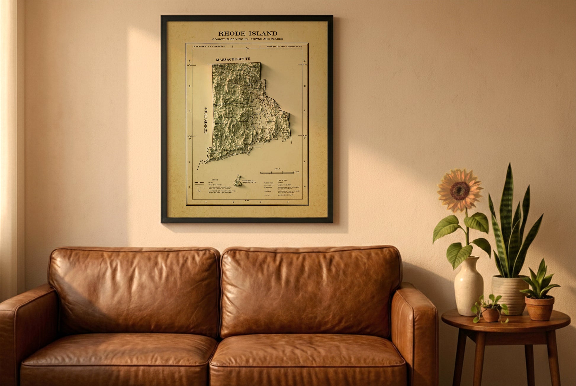 Rhode Island vintage relief map in a black frame above a brown leather sofa. Boho living room with warm sunlight, sunflower, and indoor plants on a wooden side table