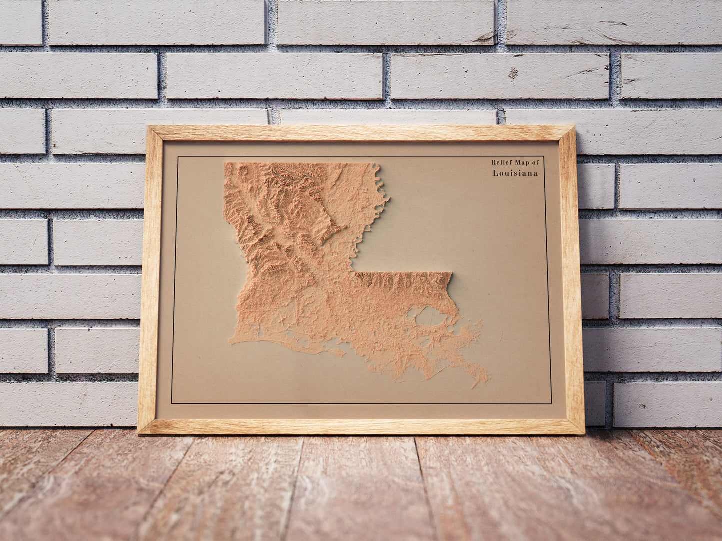 Vintage Louisiana shaded relief map in a wooden frame. Realistic terrain art print for home decor, displayed against a brick wall