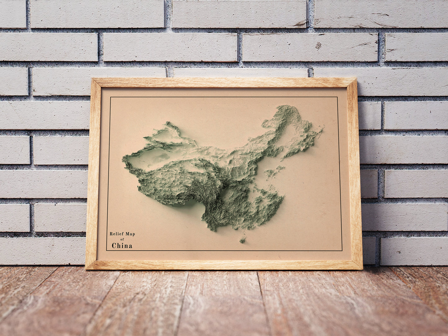 Vintage China shaded relief map in a wooden frame. Realistic terrain art print for home decor, displayed against a brick wall