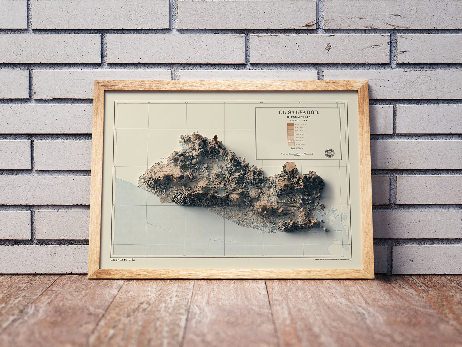 Vintage El Salvador shaded relief map in a wooden frame. Realistic terrain art print for home decor, displayed against a brick wall