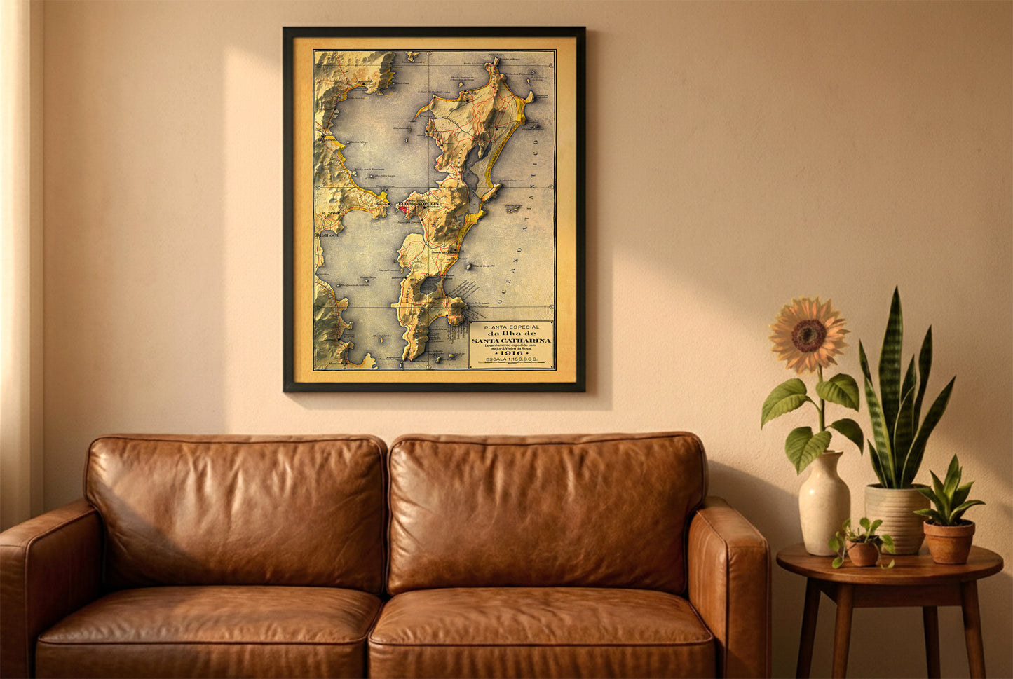 Florianopolis, Brazil, vintage relief map in a black frame above a brown leather sofa. Boho living room with warm sunlight, sunflower, and indoor plants on a wooden side table