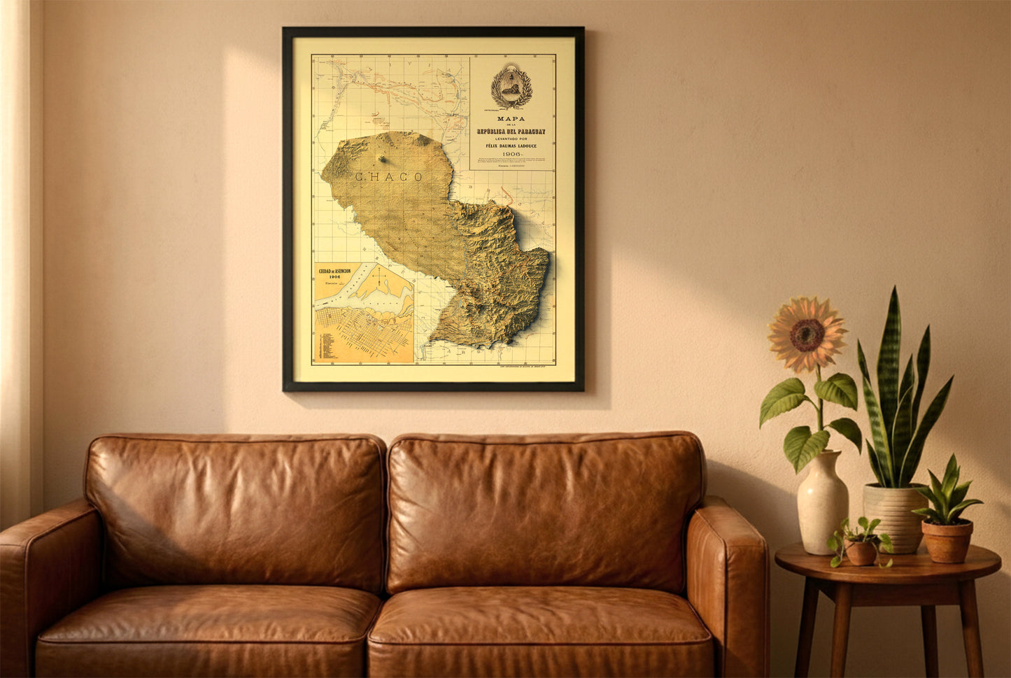 Paraguay vintage relief map in a black frame above a brown leather sofa. Boho living room with warm sunlight, sunflower, and indoor plants on a wooden side table
