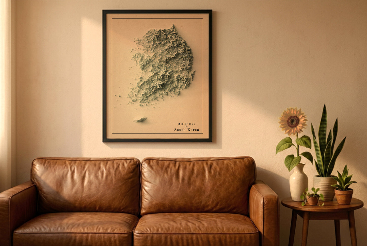 South Korea vintage relief map in a black frame above a brown leather sofa. Boho living room with warm sunlight, sunflower, and indoor plants on a wooden side table