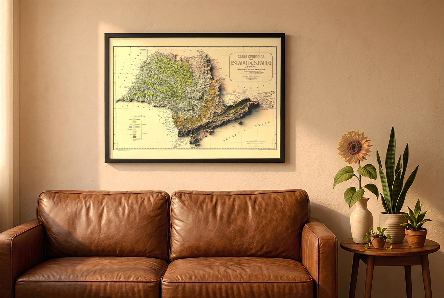 Sao Paulo, Brazil, vintage relief map in a black frame above a brown leather sofa. Boho living room with warm sunlight, sunflower, and indoor plants on a wooden side table