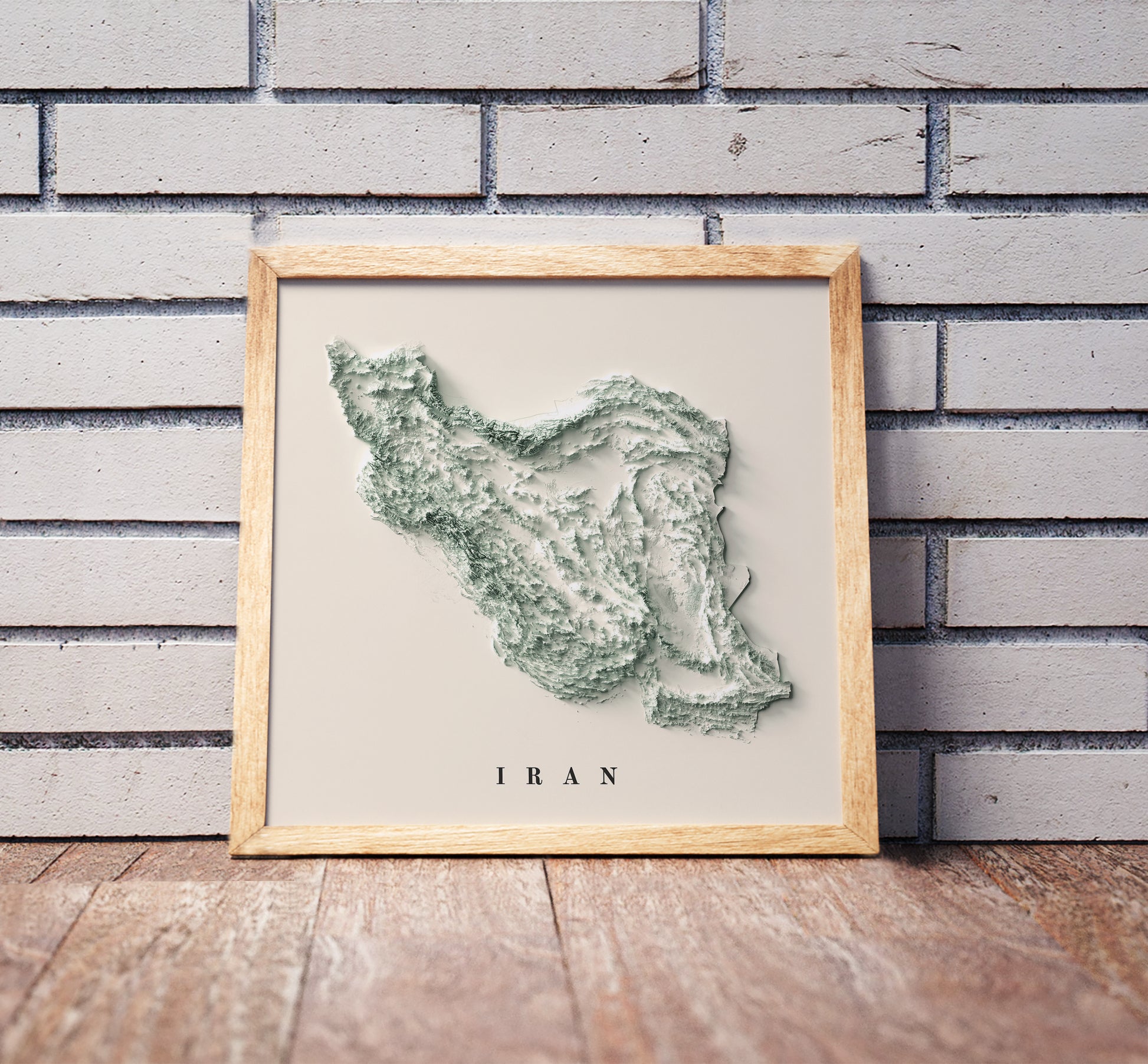 Iran shaded relief map in a wooden frame. Realistic terrain art print for home decor, displayed against a brick wall