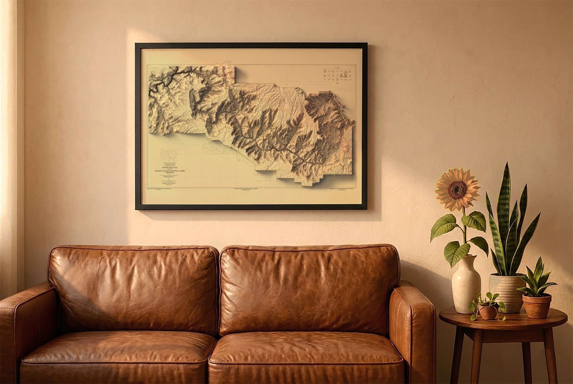 Grand Canyon vintage relief map in a black frame above a brown leather sofa. Boho living room with warm sunlight, sunflower, and indoor plants on a wooden side table