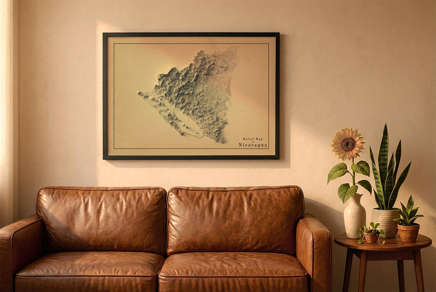 Nicaragua vintage relief map in a black frame above a brown leather sofa. Boho living room with warm sunlight, sunflower, and indoor plants on a wooden side table