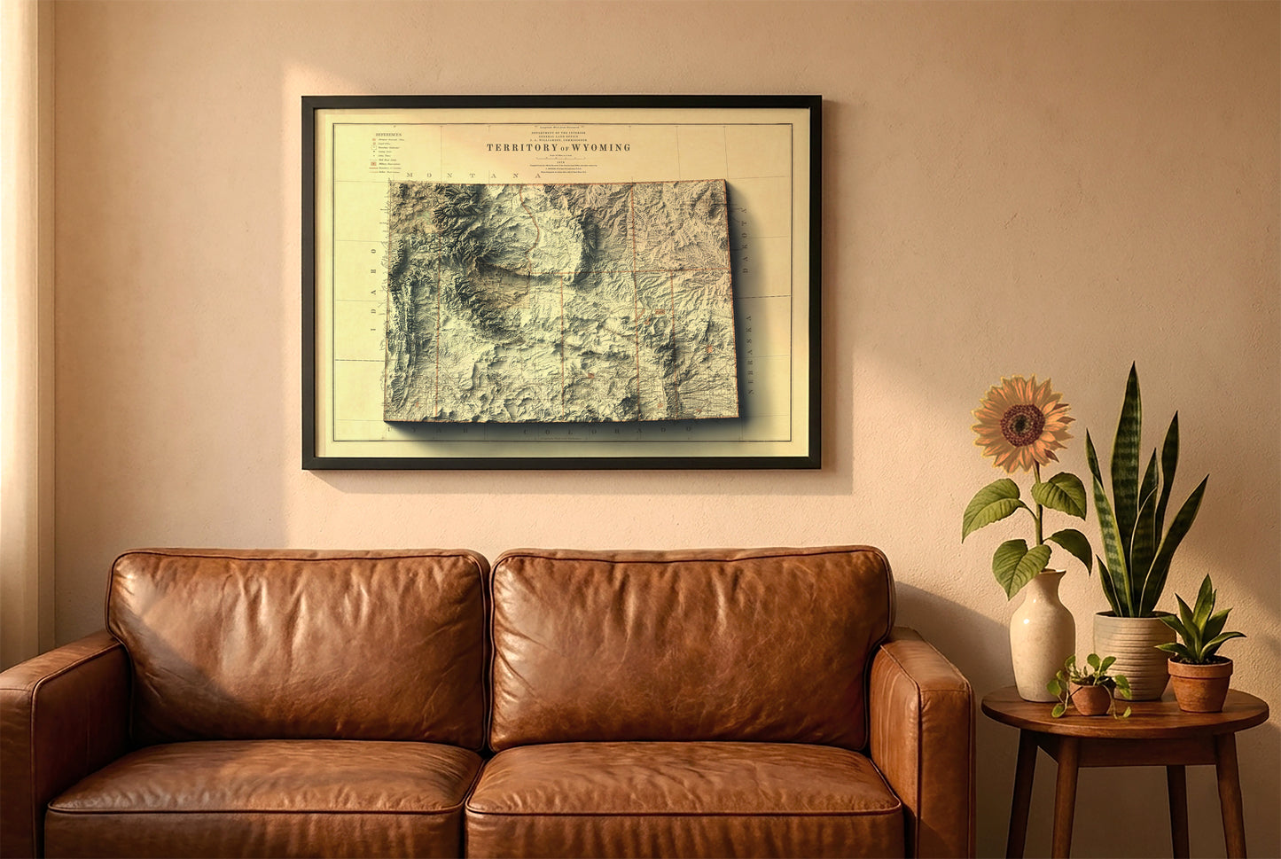 Wyoming vintage relief map in a black frame above a brown leather sofa. Boho living room with warm sunlight, sunflower, and indoor plants on a wooden side table
