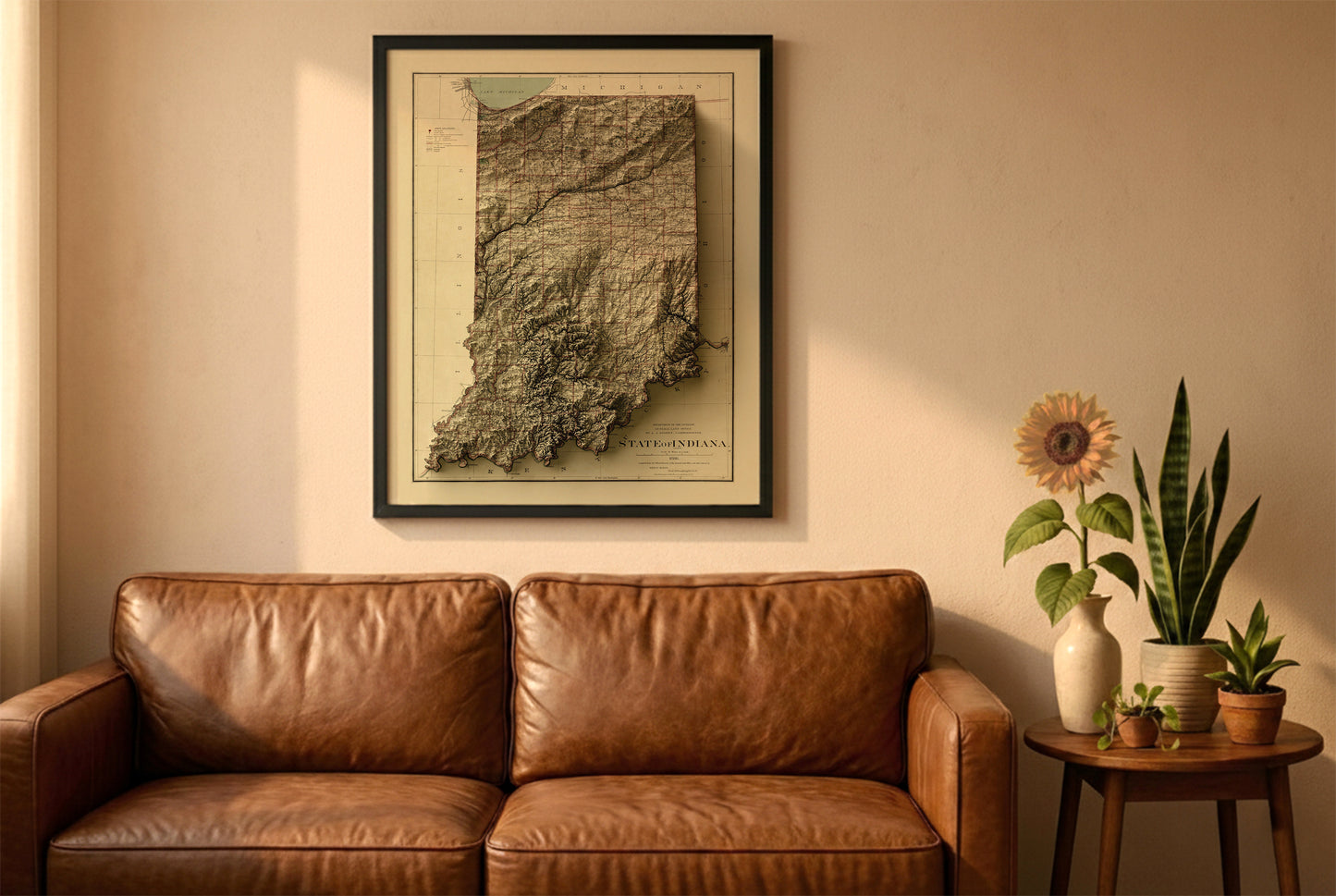 Indiana vintage relief map in a black frame above a brown leather sofa. Boho living room with warm sunlight, sunflower, and indoor plants on a wooden side table