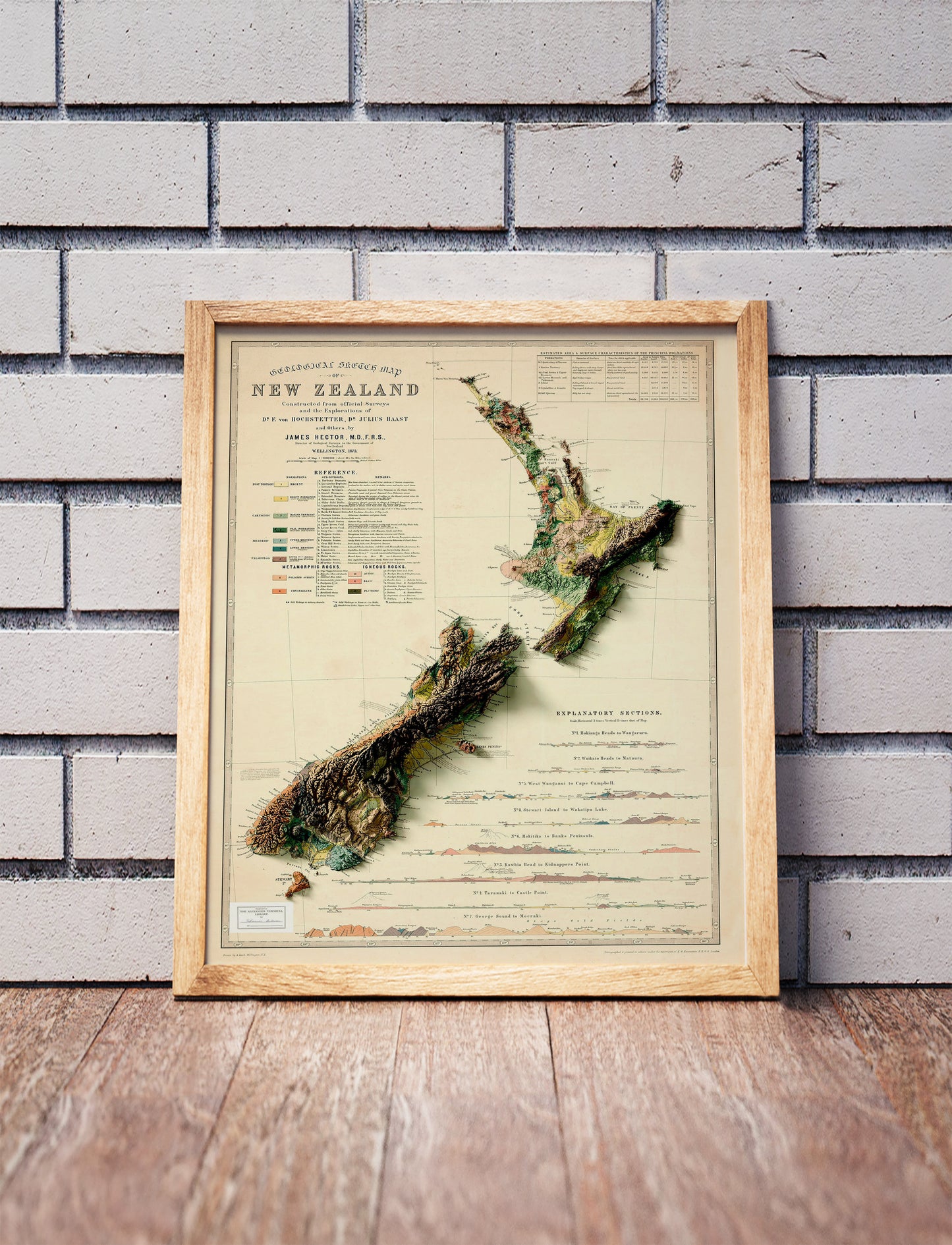 Vintage New Zealand state shaded relief map in a wooden frame. Realistic terrain art print for home decor, displayed against a brick wall