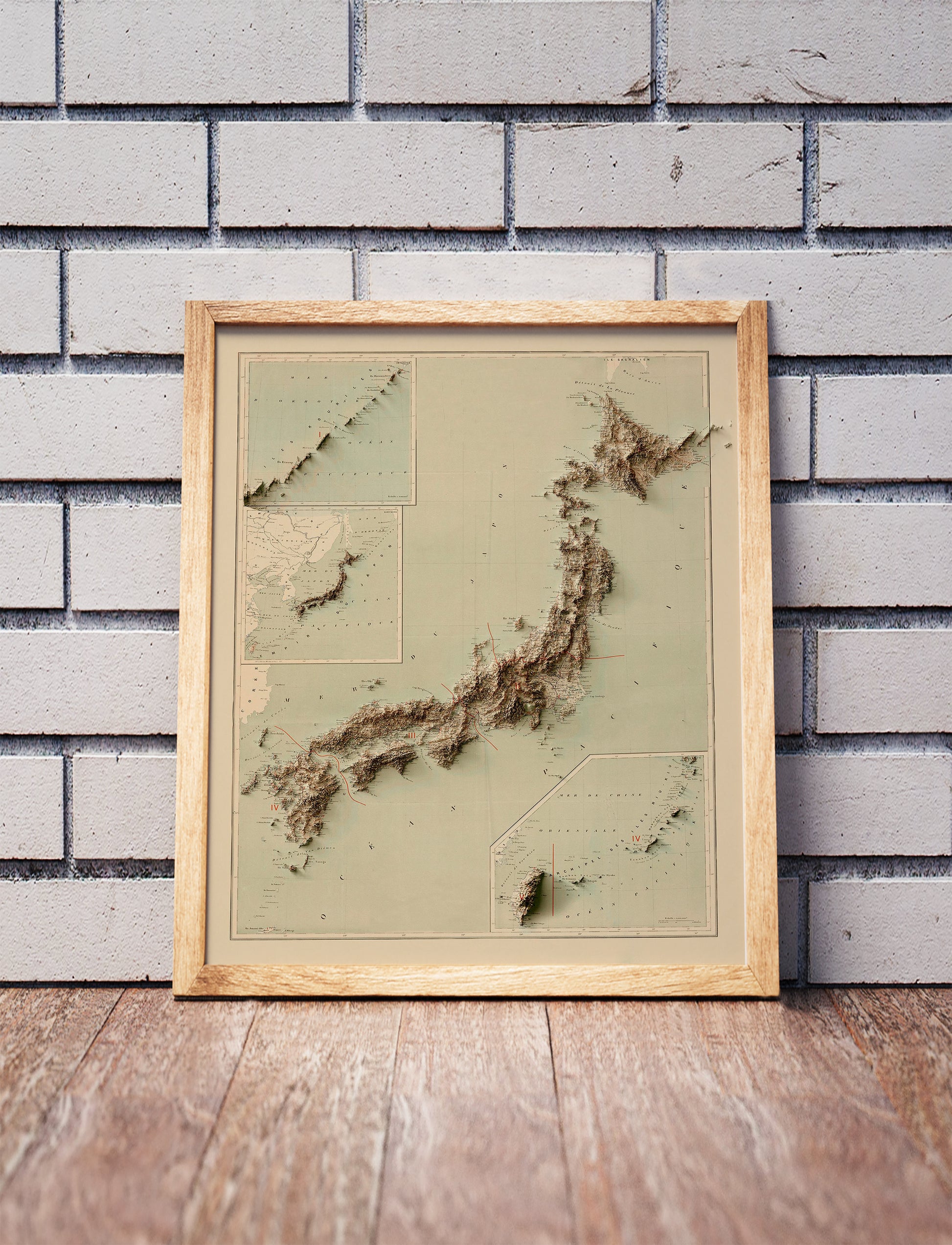 Vintage Japan shaded relief map in a wooden frame. Realistic terrain art print for home decor, displayed against a brick wall