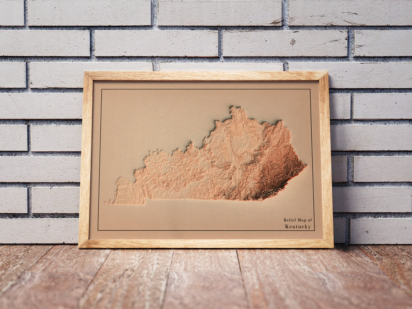 Vintage Kentucky shaded relief map in a wooden frame. Realistic terrain art print for home decor, displayed against a brick wall