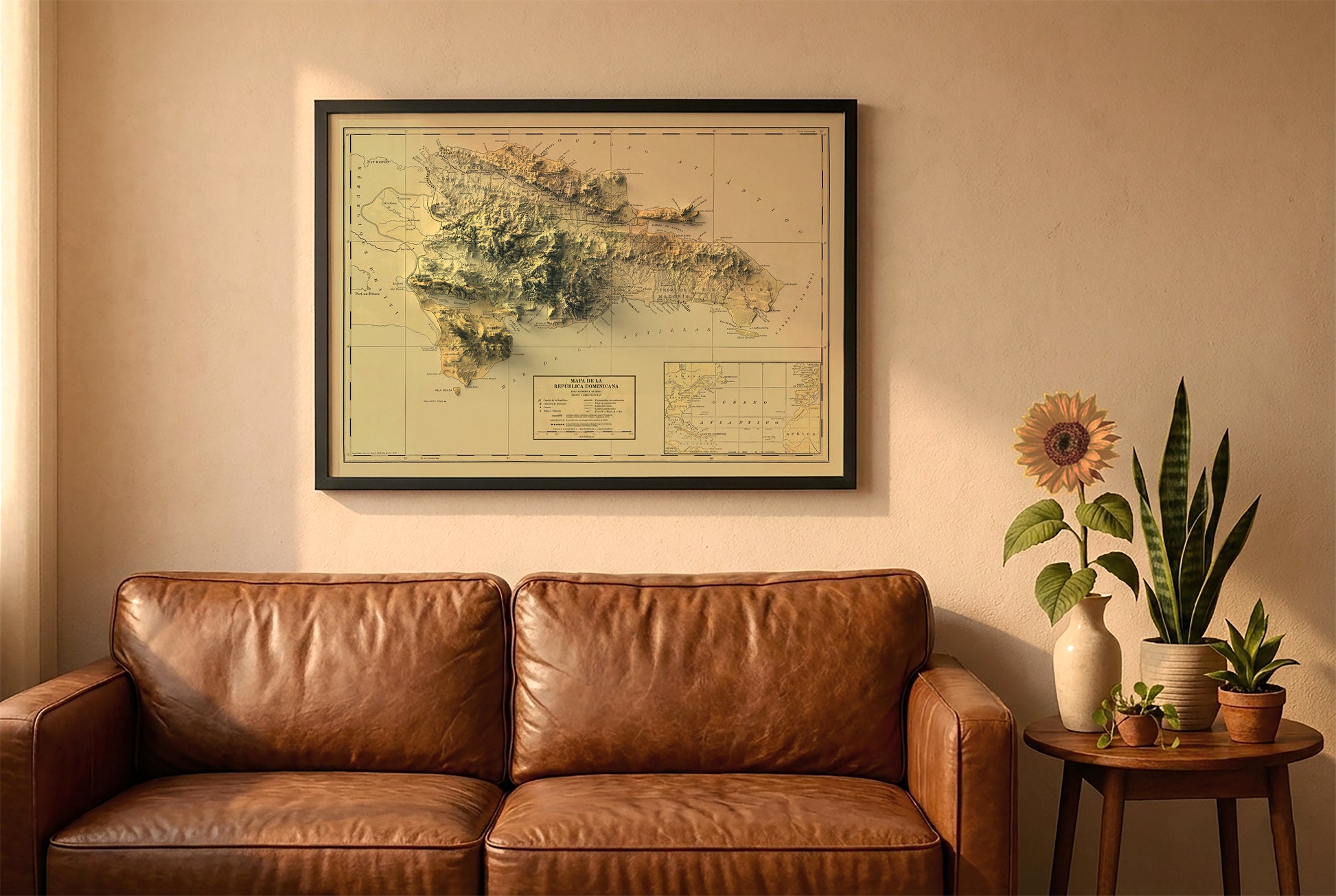 Dominican Republic vintage relief map in a black frame above a brown leather sofa. Boho living room with warm sunlight, sunflower, and indoor plants on a wooden side table